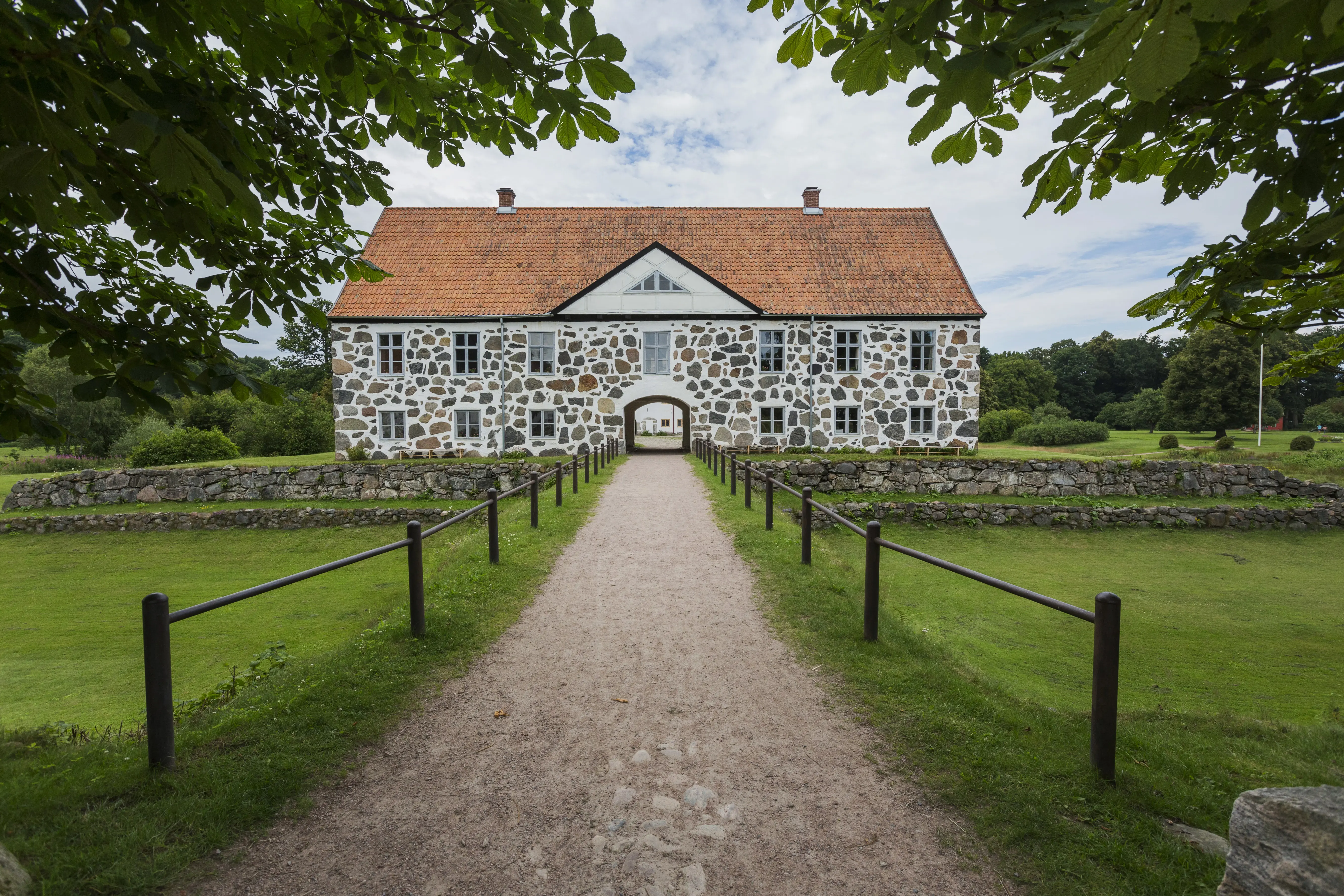 Hovdala slott, arrendatorflygeln. Stenbyggnad i två våningar. En väg leder över en torrlagd vallgrav och in genom en port till gårdsplanen.