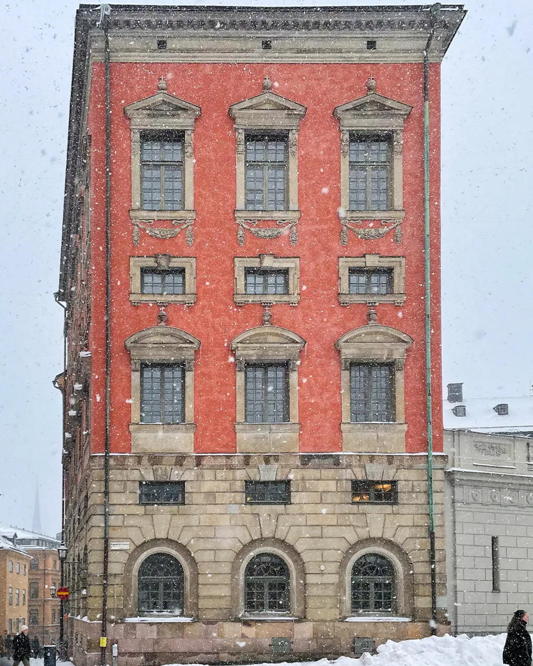 Oxenstiernska palatsets röda fasad en vinterdag med snöfall.