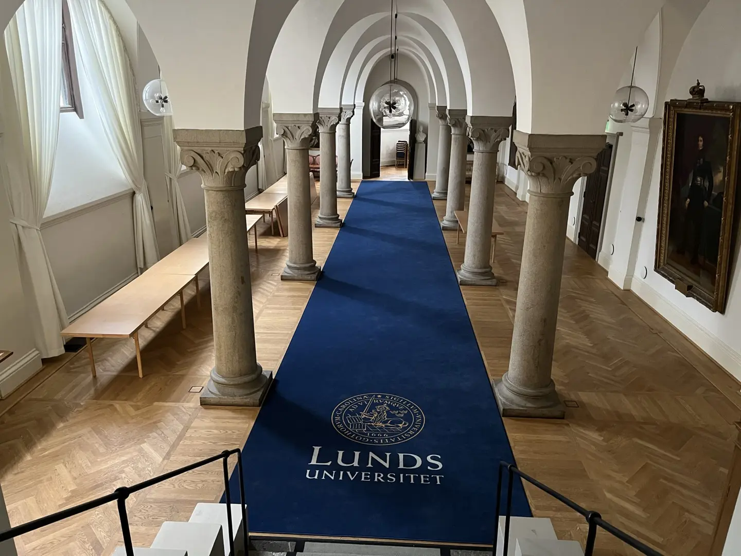 Korridor med pelare och en lång blå matta med texten "Lunds universitet".
