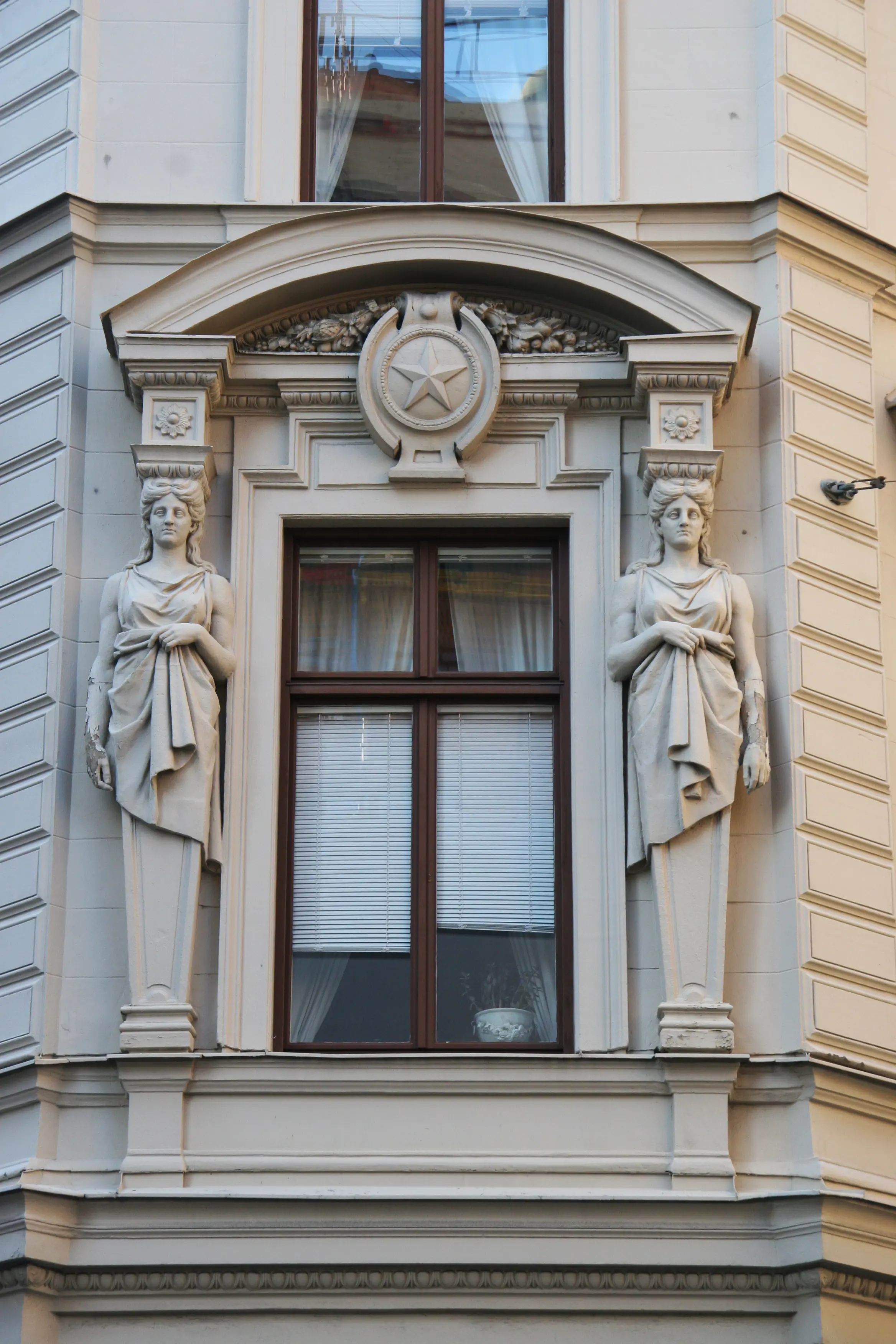 Detalj av kvarteret Tigerns fasad. Ett fönster ramas in av stendekor, Nordstjernans stjärnsymbol flankerad av två karyatider.