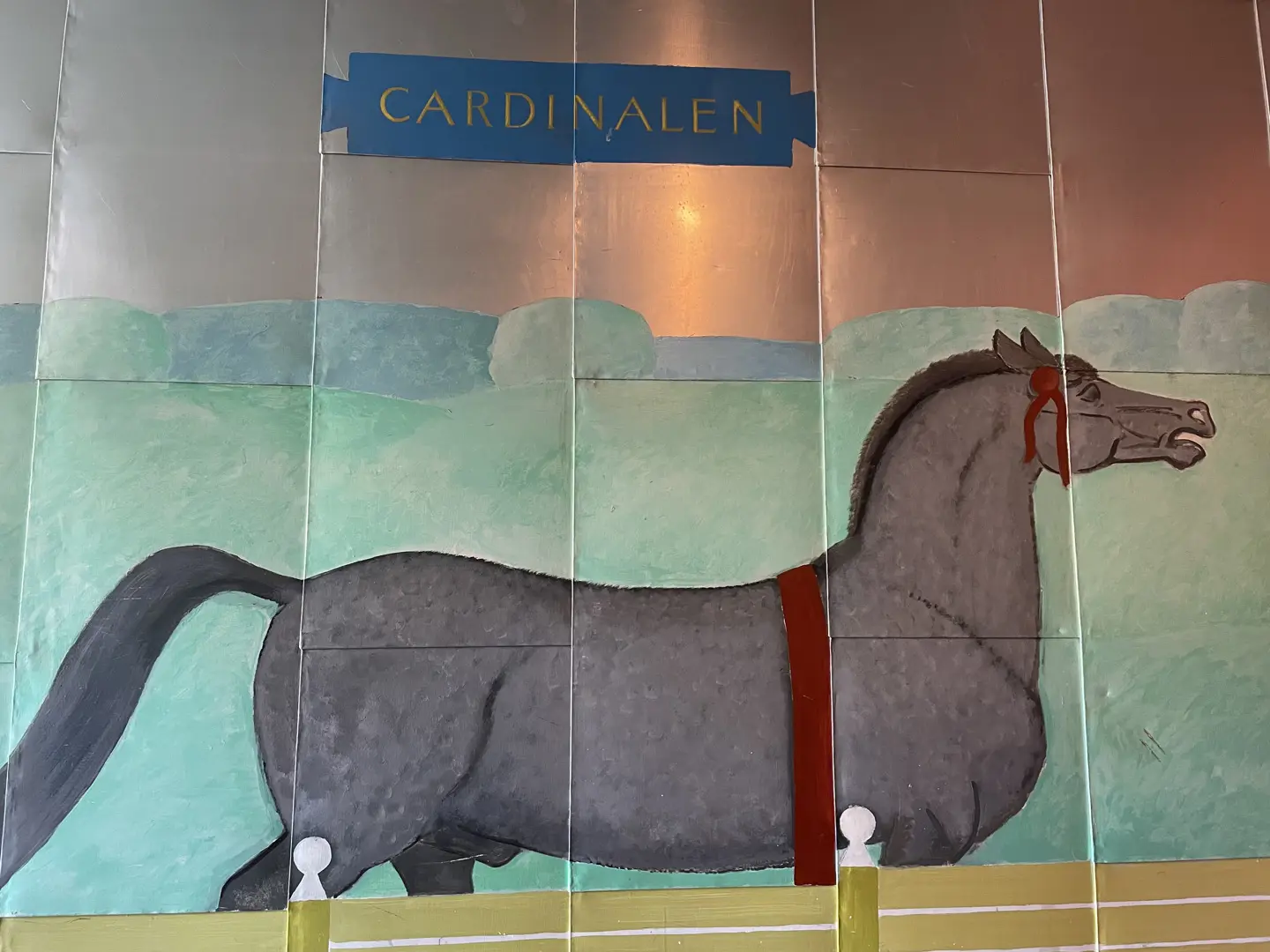 På en plåtklädd vägg är en häst målad, med överskriften "Cardinalen".