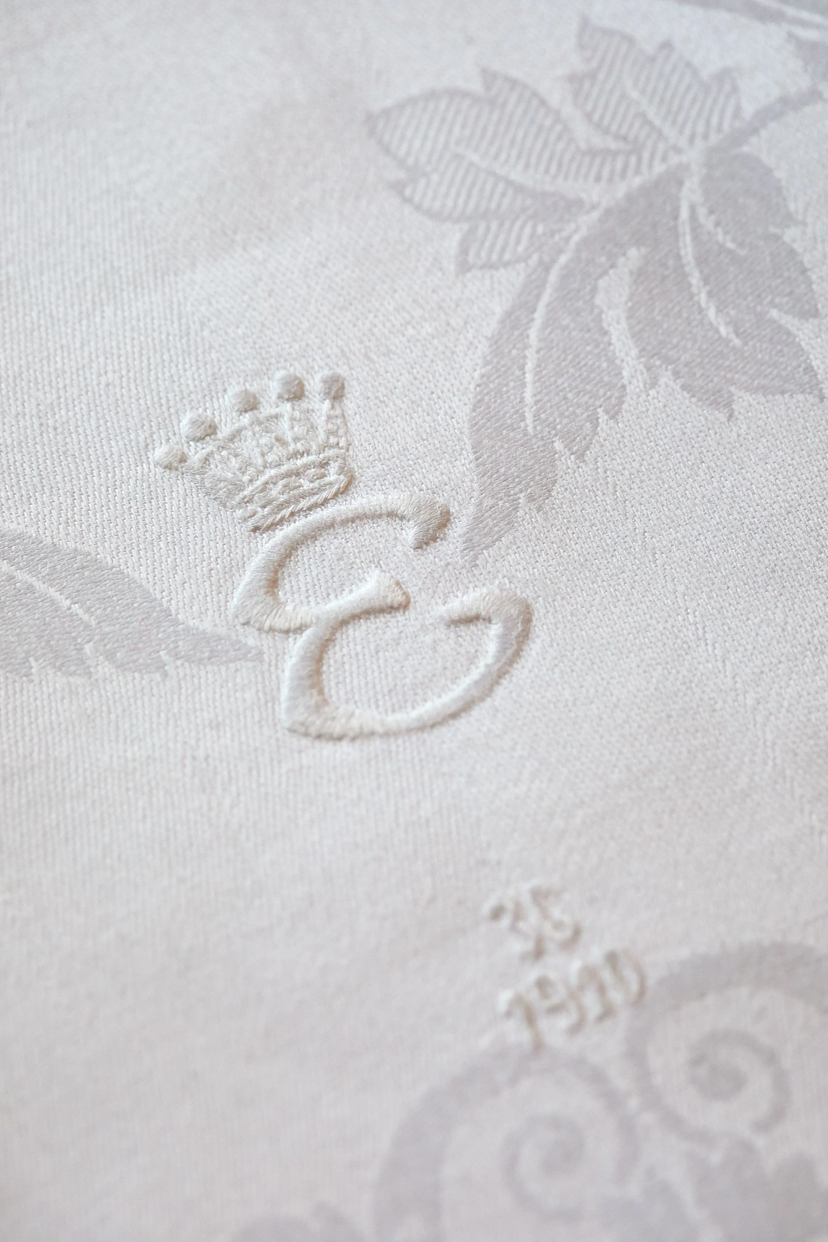 Detalj från linneservett med broderat E och årtalet 1910.