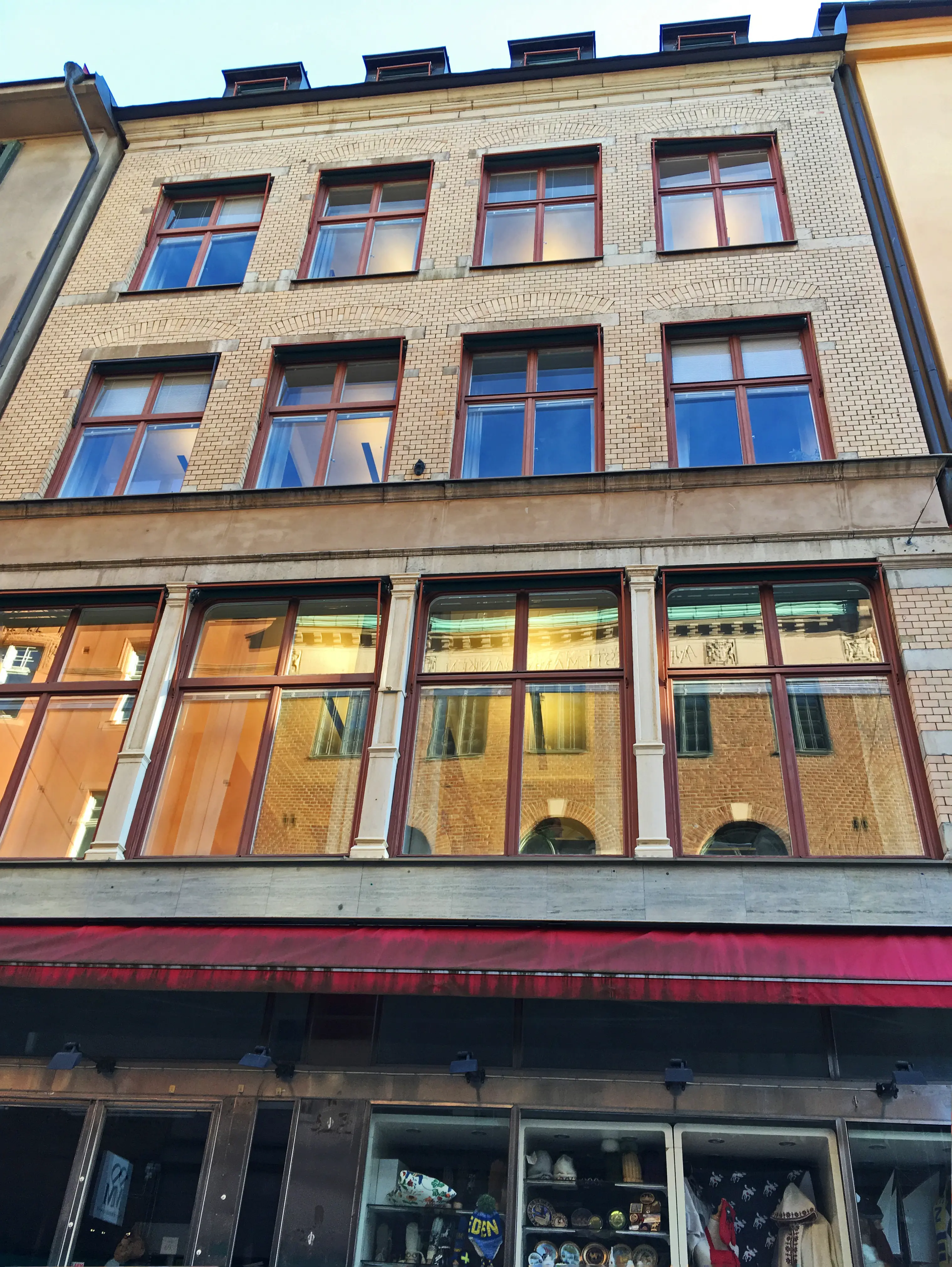 Drottninggatan 12. Smal byggnad i fyra våningar med gul tegelfasad och tak-kupor.