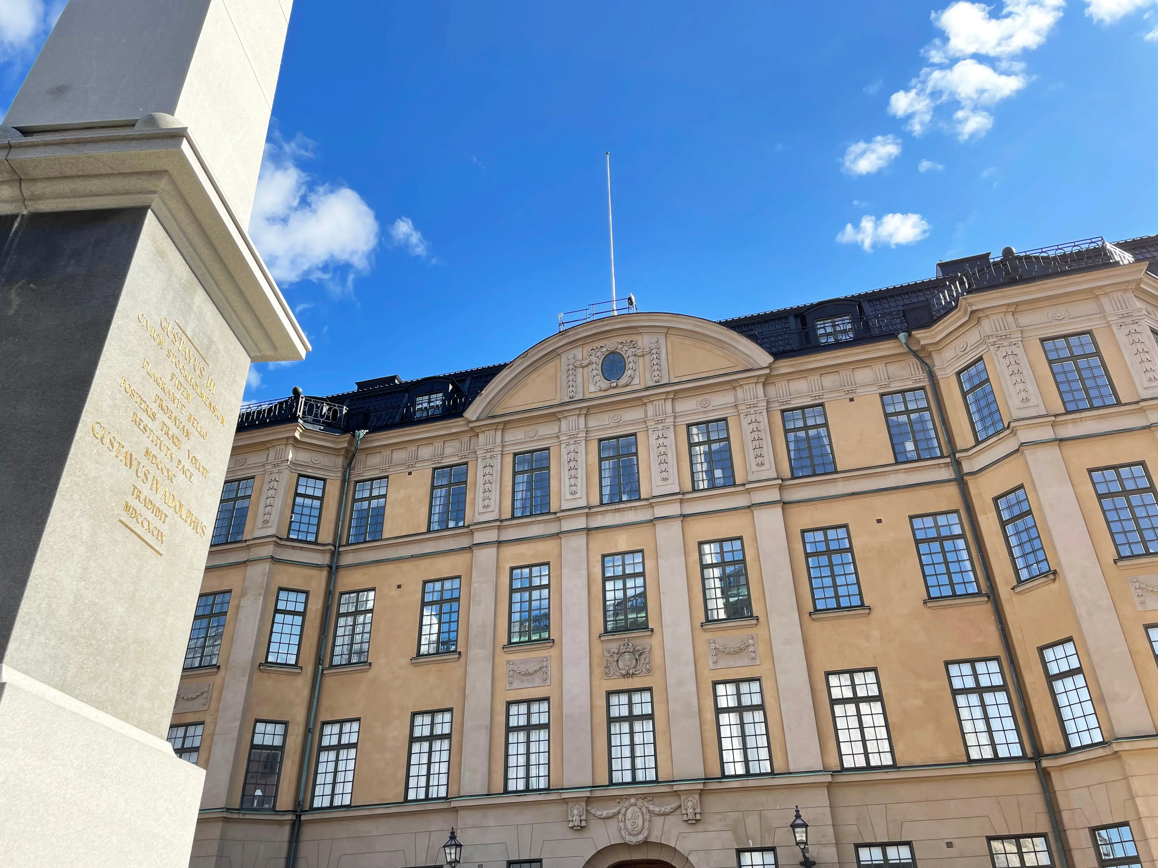 Hovförvaltningens hus. En gulbrun klassicistisk byggnad med liten, rundad praktgavel. Framför huset står en stenobelisk.