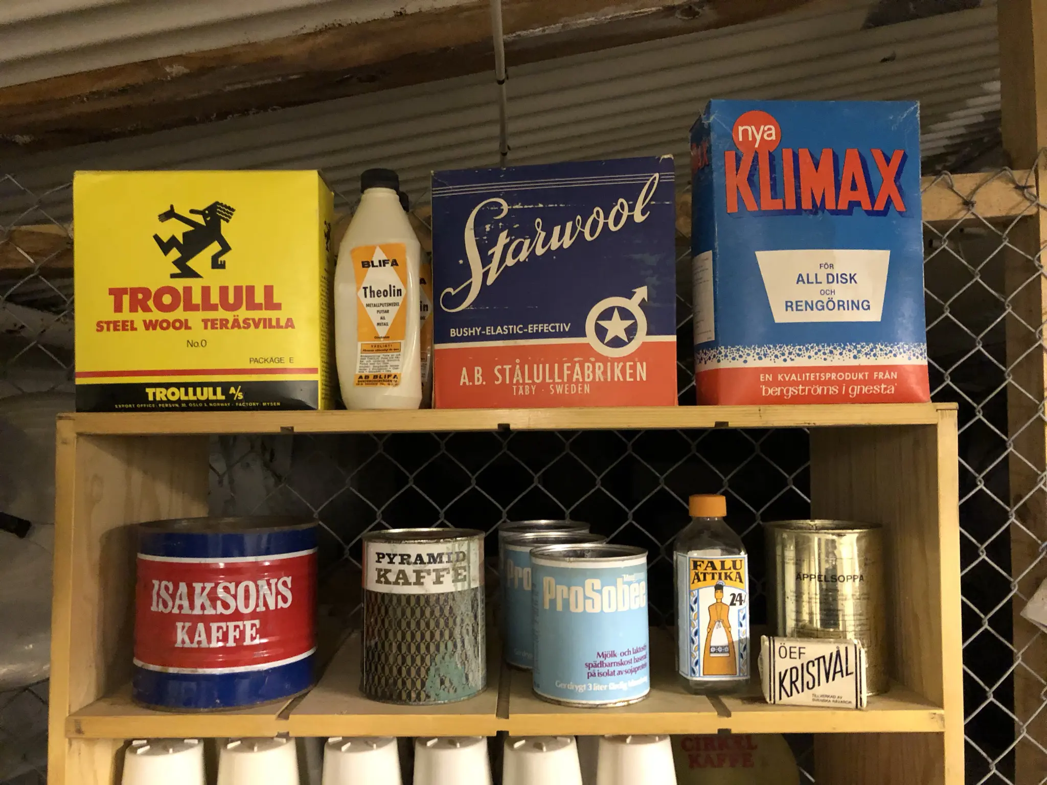 Bodens fästning. Detalj från kökshylla med gamla förpackningar, bland annat Trollull, Isakssons kaffe, Falu ättika och ÖEF kristvål.