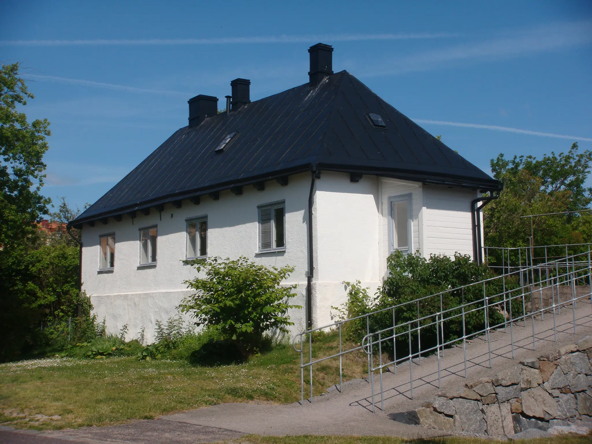 Vaktbyggnaden på Stumholmen. En vit-putsad byggnad med svart plåt-tak.