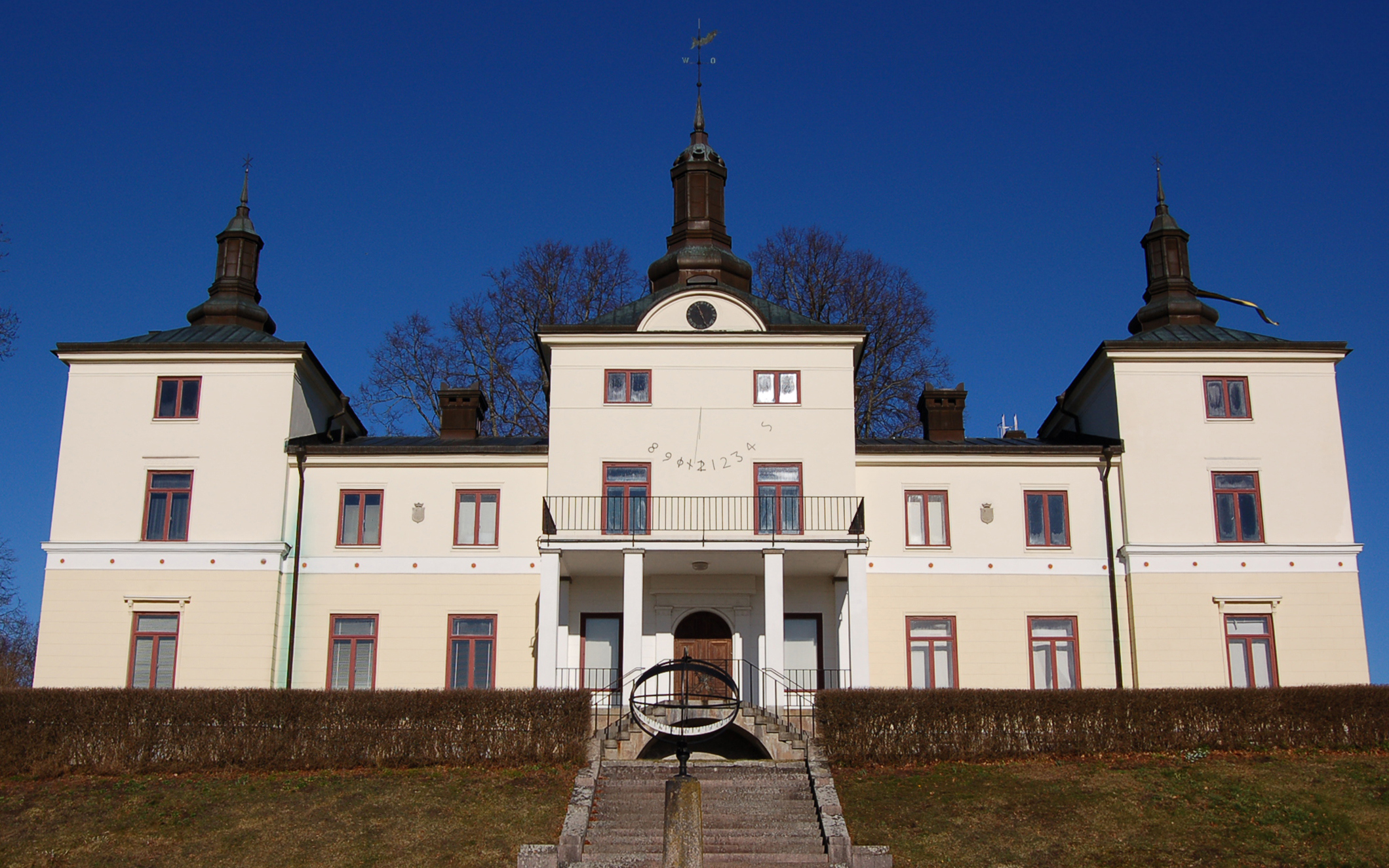 Stenhammar, litet slott i ljusgul puts, med solur på fasaden och lanterniner på taket.