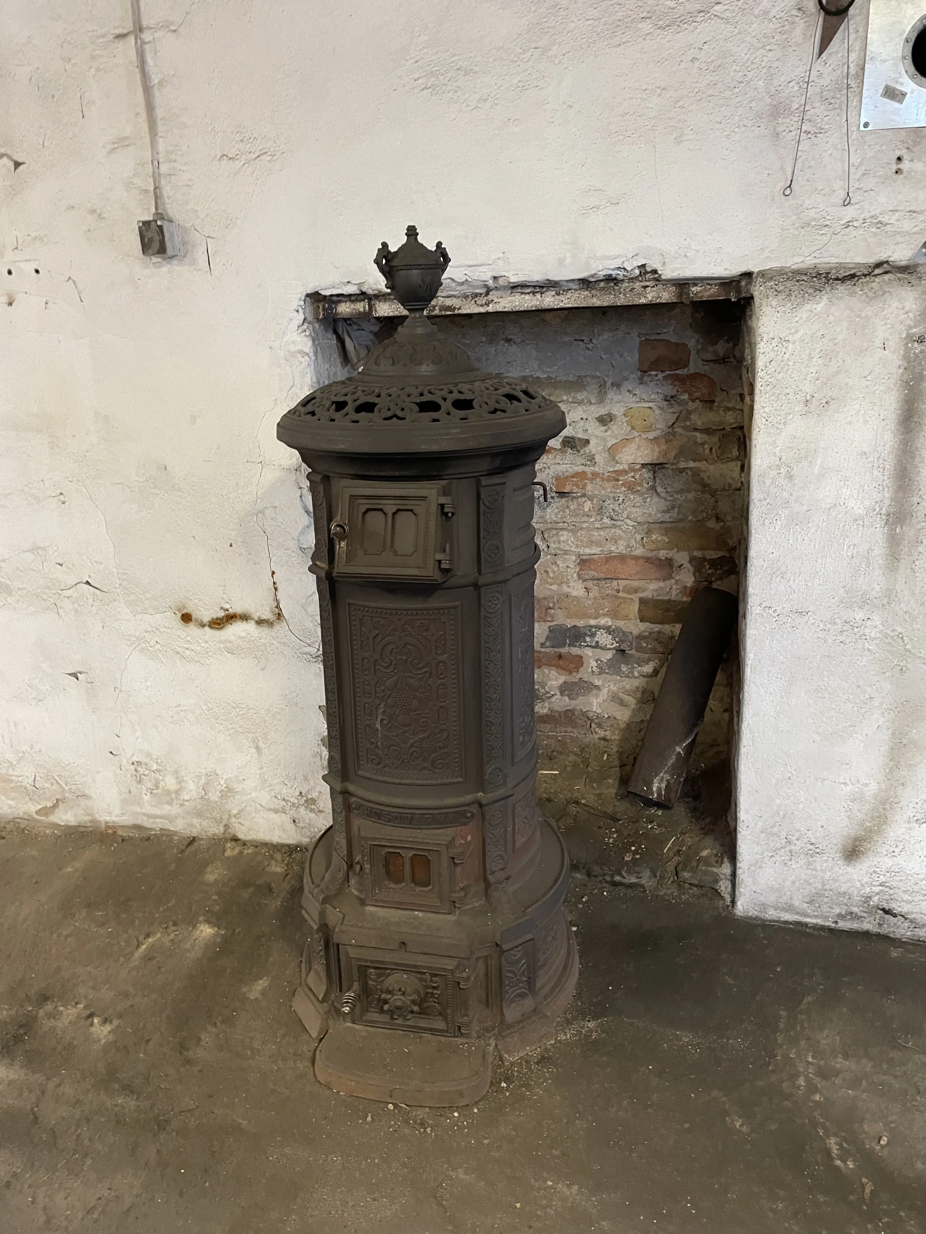 Gjutjärnskamin på betonggolv och putsade väggar.