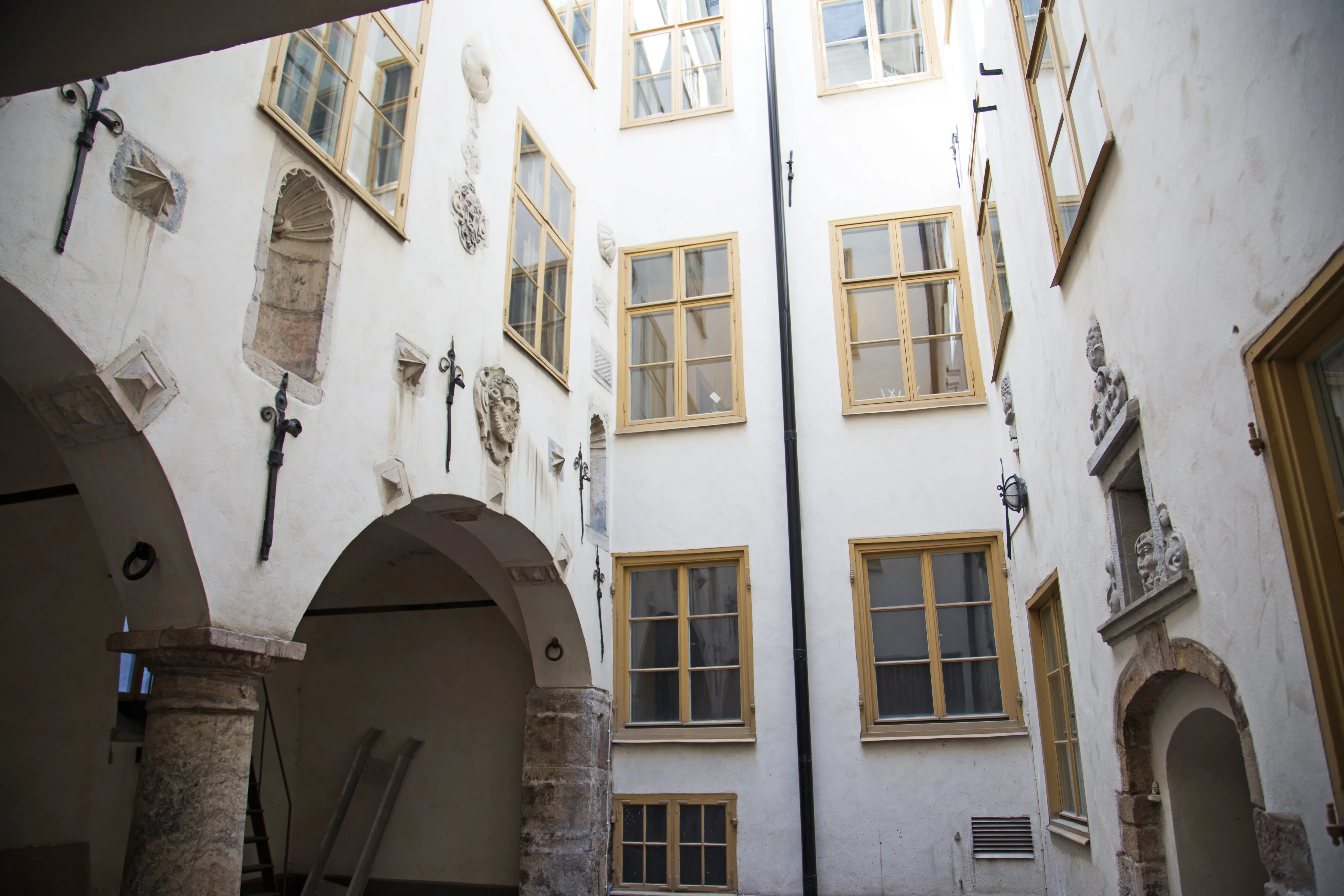 Beijerska husets innergård. Fasaderna är vitputsade och utsmyckade med ankarslut och stendekorationer. Fönstren har gula snickerier.