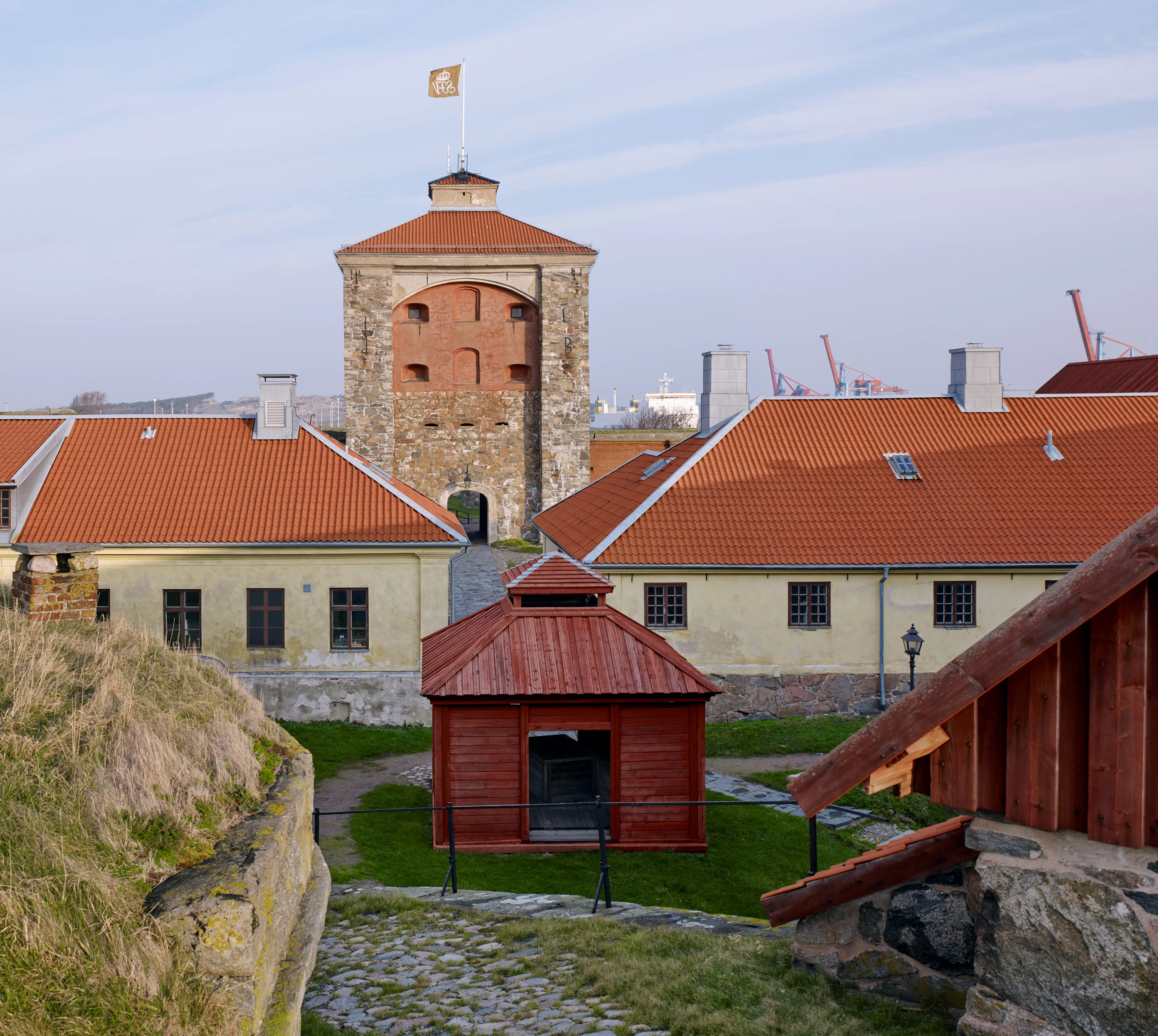 En av gårdarna i Nya Älvsborgs fästning, med en rödmålad brunnsöverbyggnad. I bakgrunden två förläggningsbyggnader och tornet.