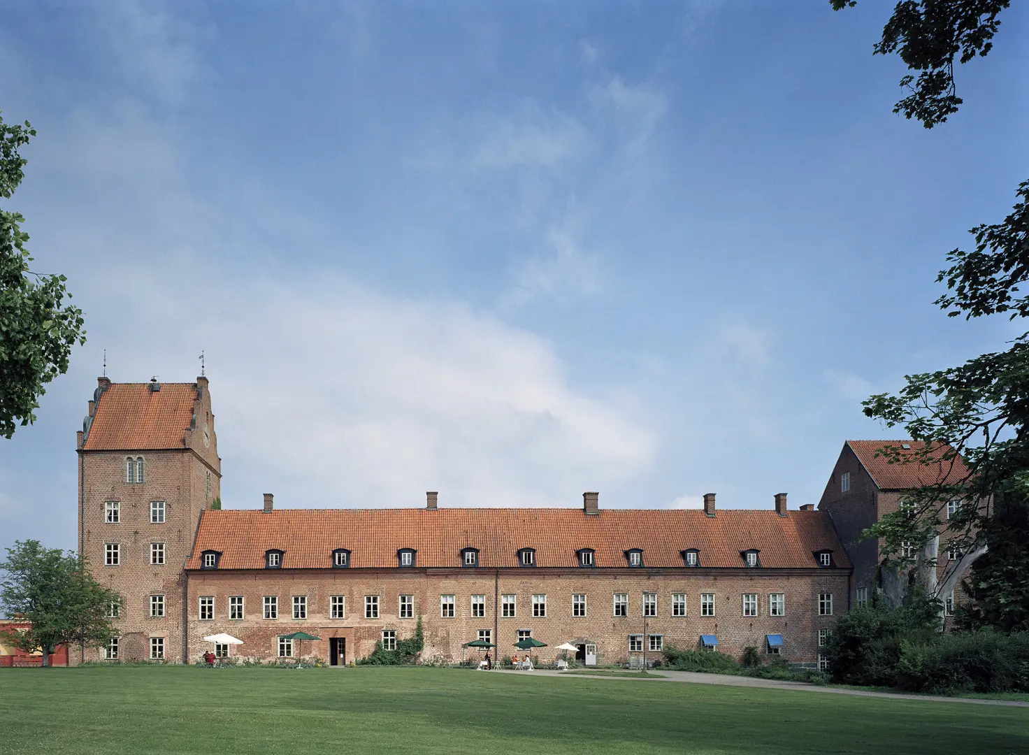 Bäckaskog slott sett på avstånd, med en gräsmatta i förgrunden.