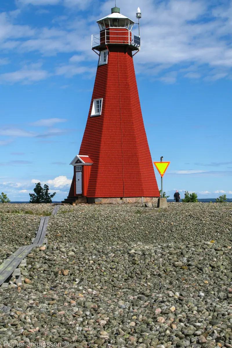 Malörens fyr med en stenig strand i förgrunden.