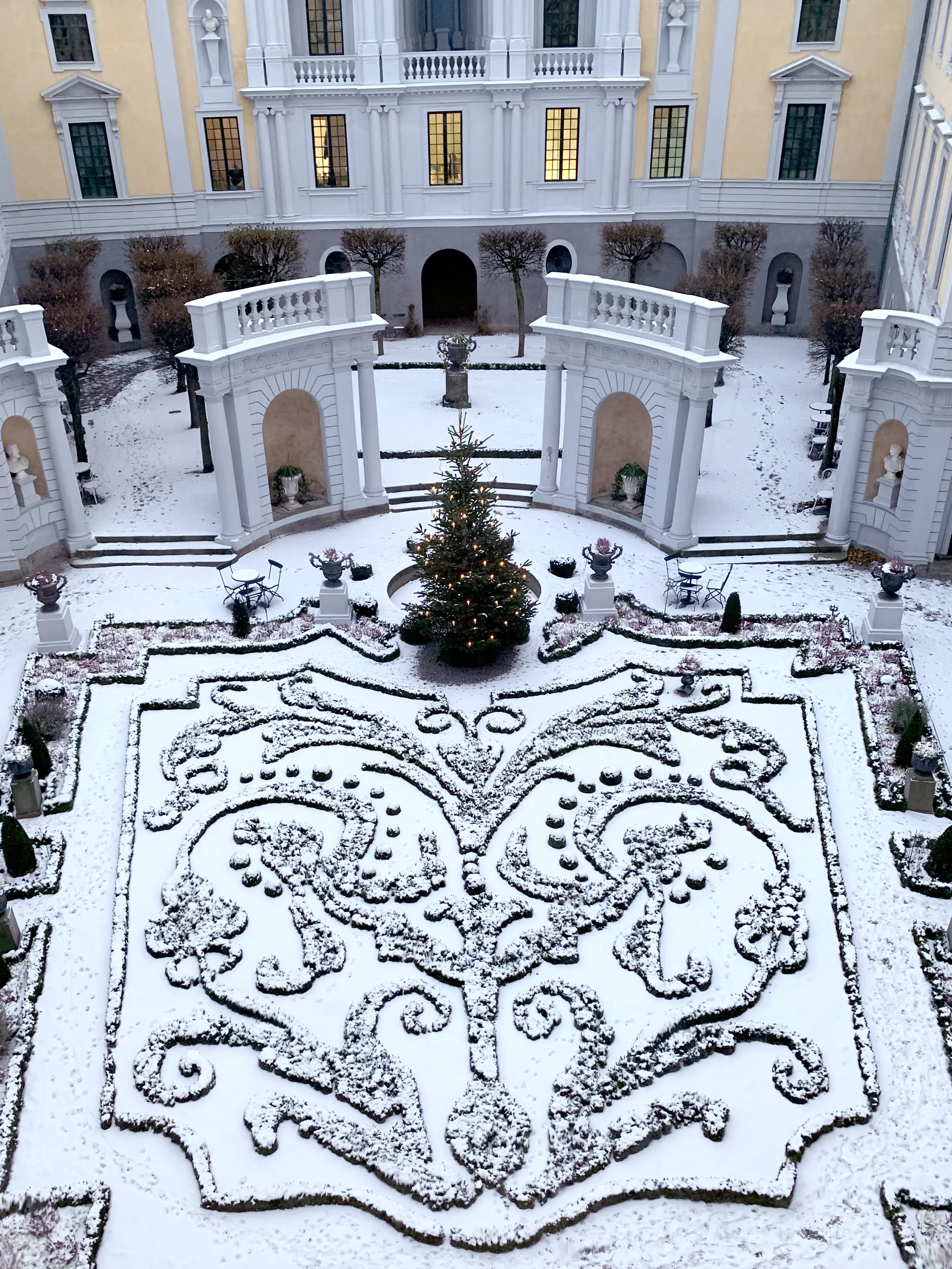 Tessinska palatsets gård sedd uppifrån. Barockträdgården är täckt med snö, en julgran står invid fontänen.