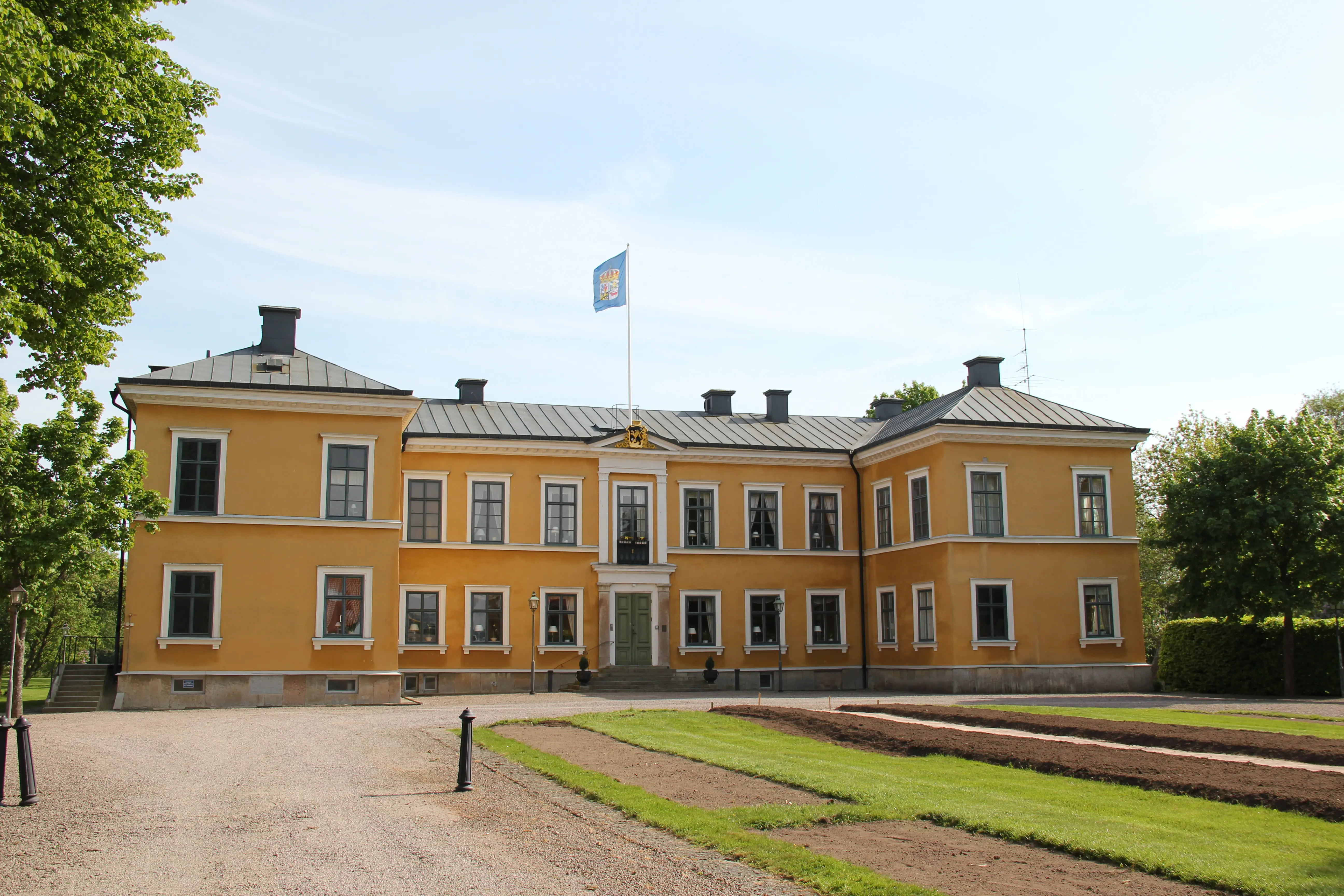 Huvudbyggnaden, Marieholm. Entrésidan. En gulputsad tvåvåningsbyggnad i klassicistisk stil. Sommar och grönska.