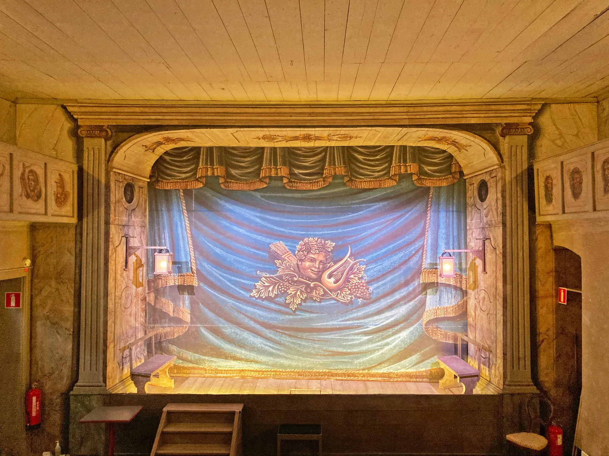 Vadstena gamla teater. Scenen med nedfälld ridå, som har målade draperingar och guldfransar.