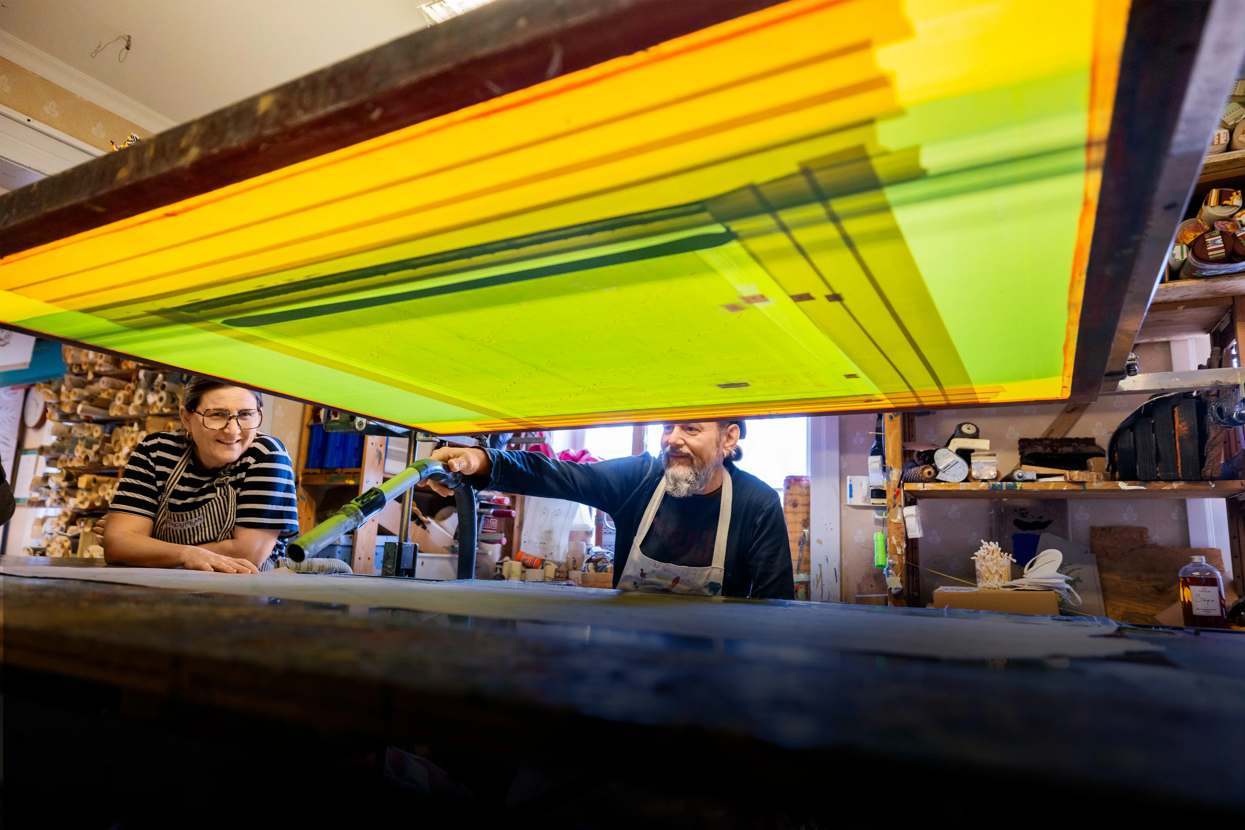 en man och en kvinna tittar in under en stor apparat och dammsug/blåser torrt.