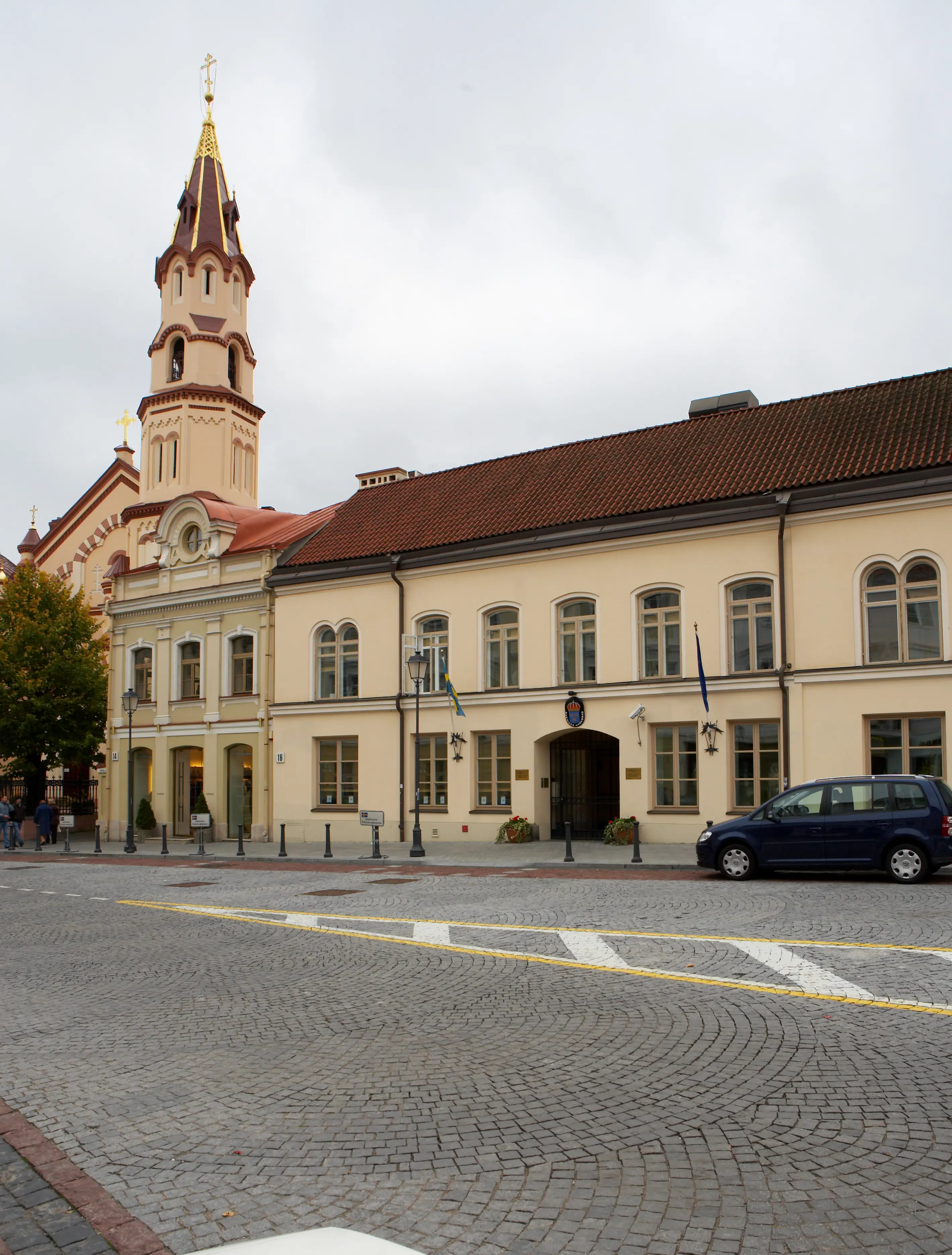 Ambassaden i Vilnius. En gulputsad tvåvåningsbyggnad med tegeltak vid en kullerstens-gata.