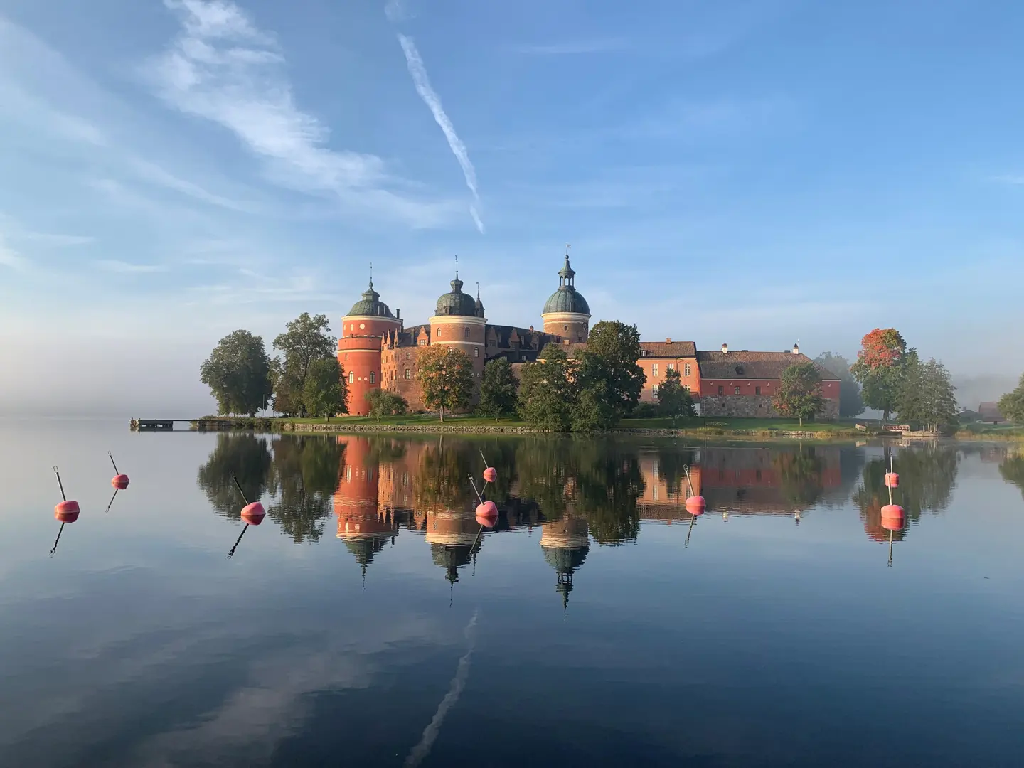 Gripsholms under klarblå himmel som speglar sig mot vattnet.