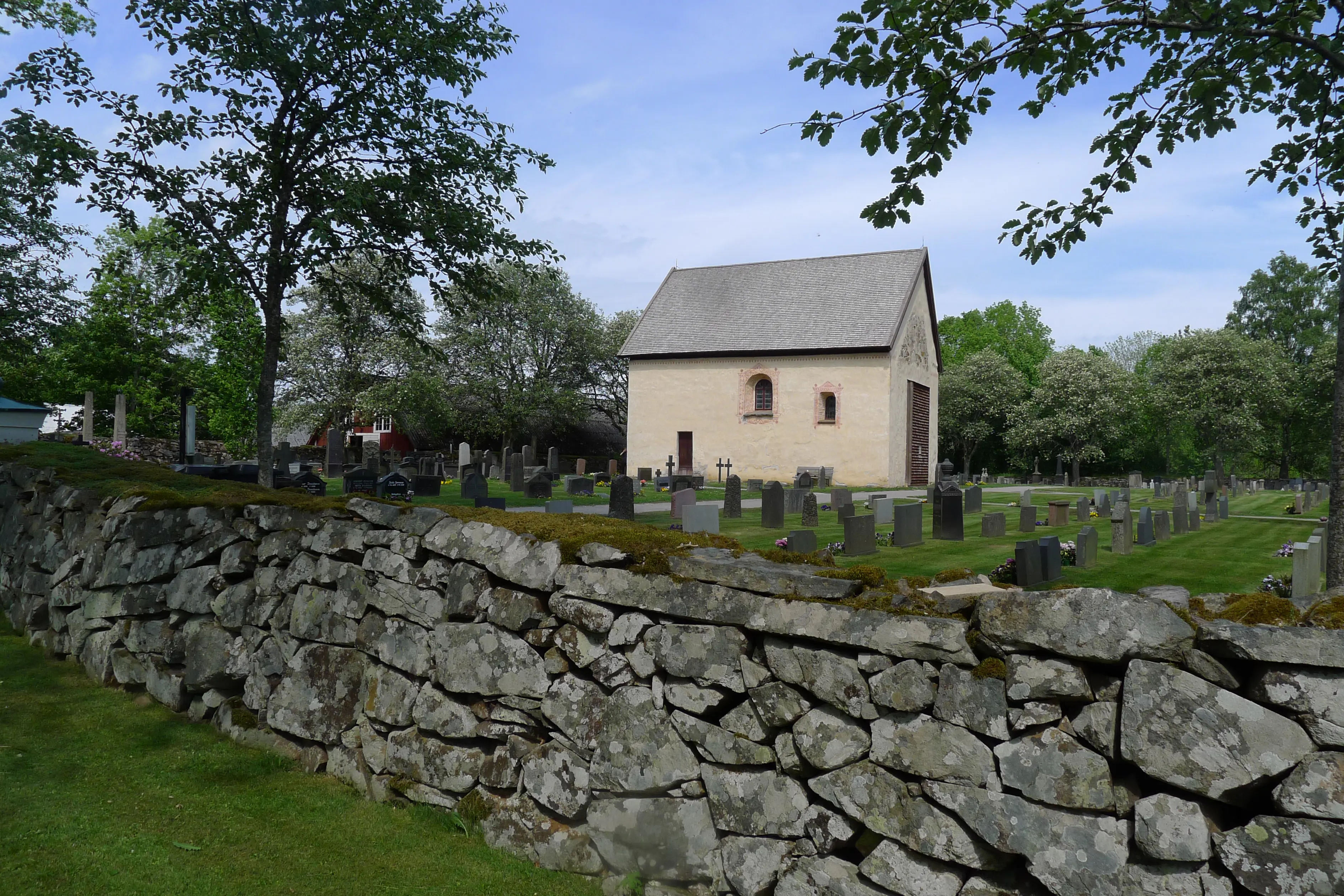 Dädesjö gamla kyrka, omgiven av kyrkogården. Runt kyrkogården går en stenmur.