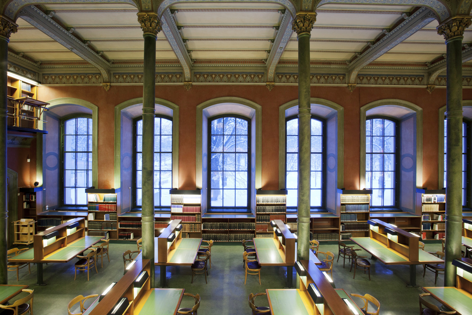 Stora läsesalen, Kungliga biblioteket. Högt i tak, stora fönster. Golv, pelare och läseplatser går i grönt.