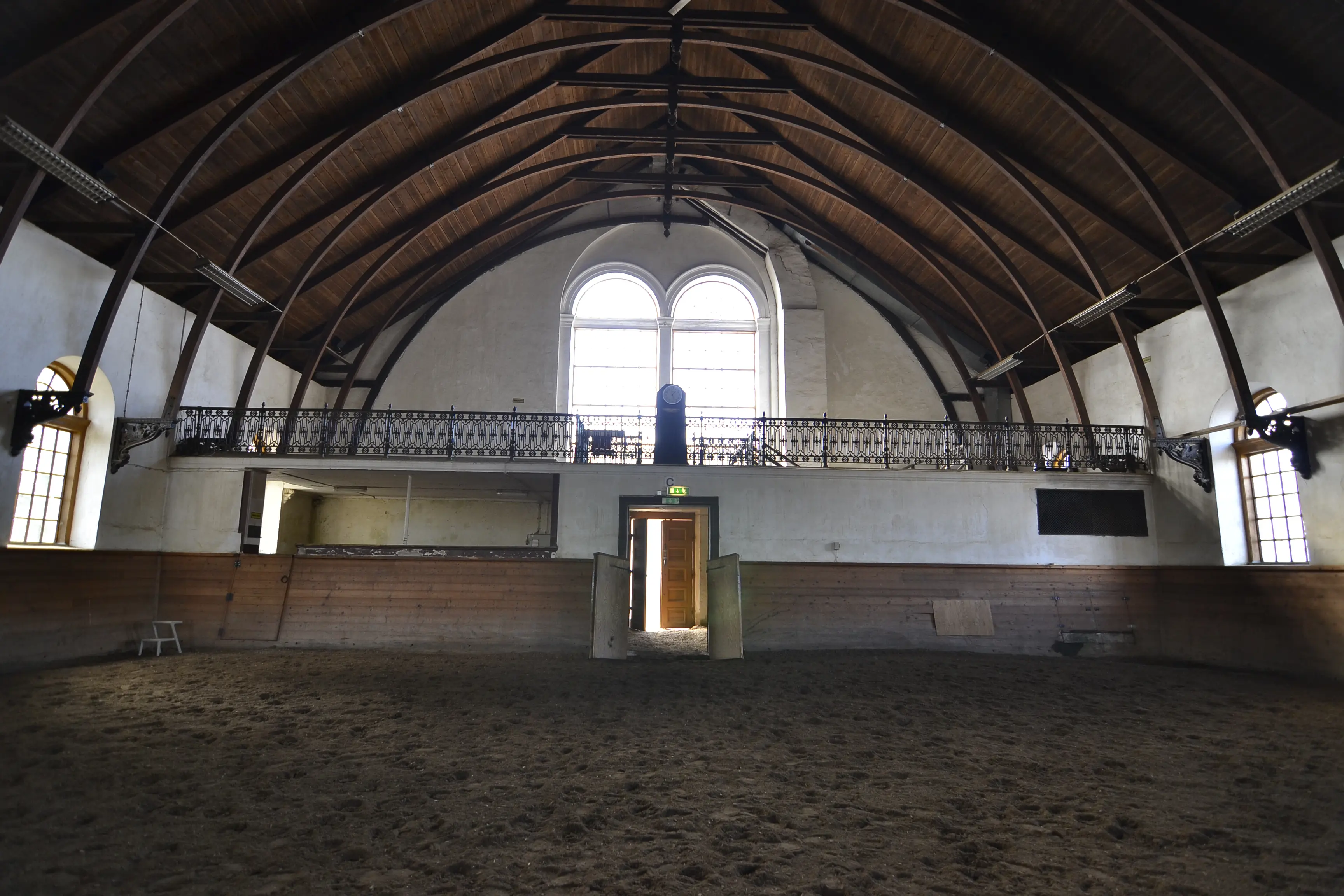 Interiör, vita ridhuset. Ridmanege med välvda takbågar och höga, smala fönster. En avsats med smidesräcke ger överblick.