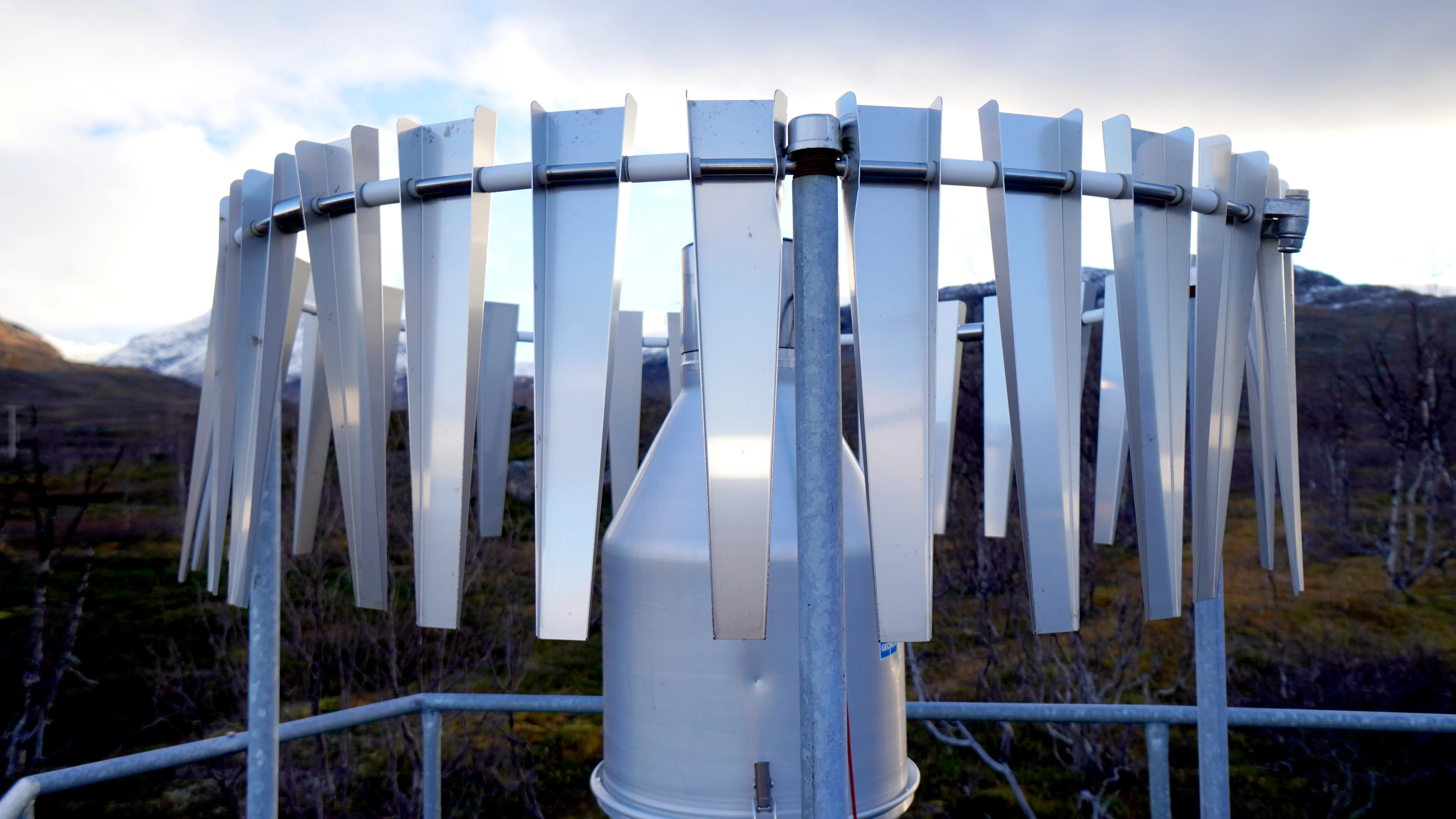 Ett mätinstrument i metall som ser ut som en lång stång med en rundel med flärpar som hänger ner.