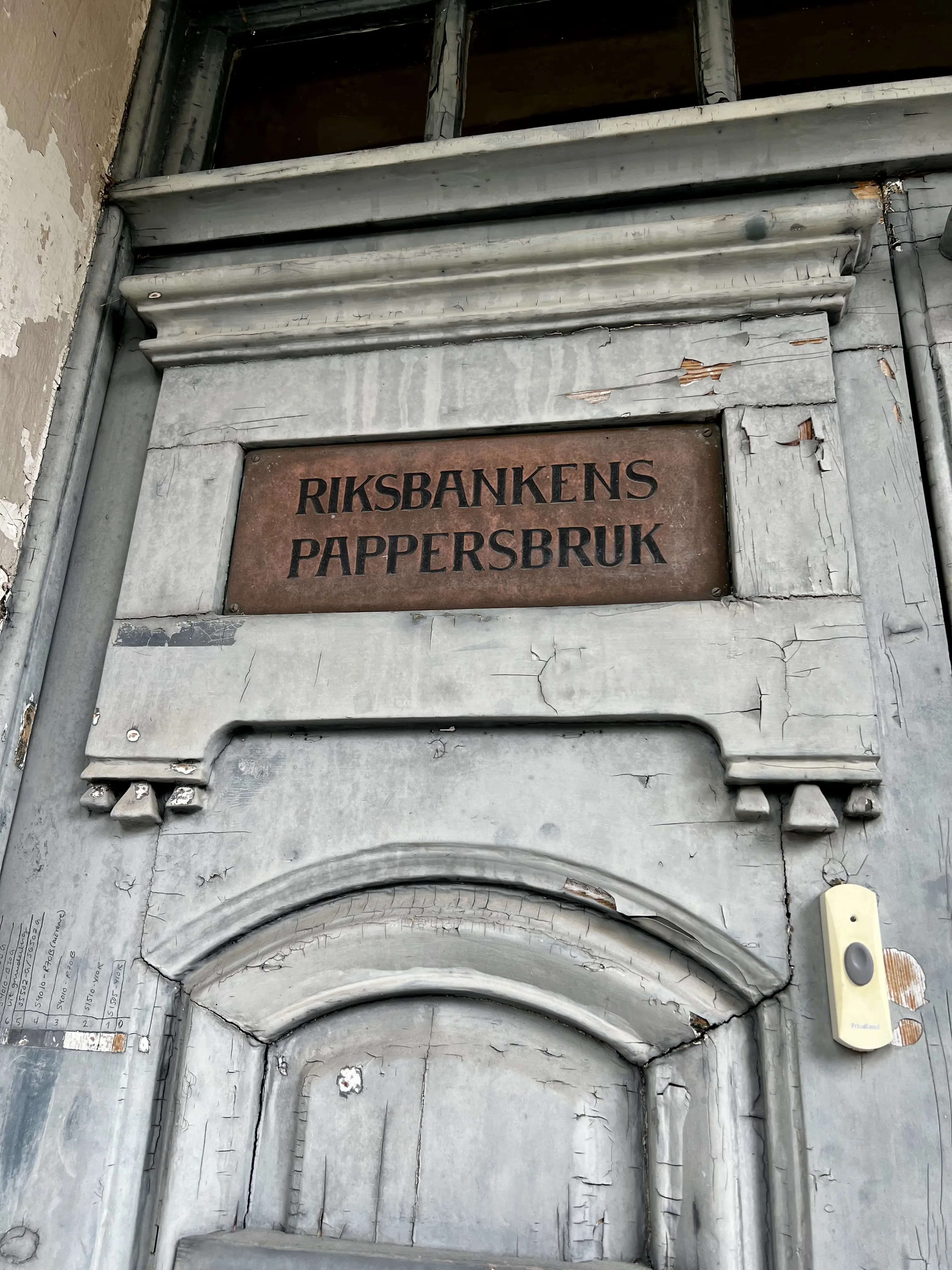 Förvaltarbostaden, Tumba bruk. Detalj från en dörr. Inramad av snidade trälister sitter en plåtskylt med texten "Riksbankens pappersbruk".