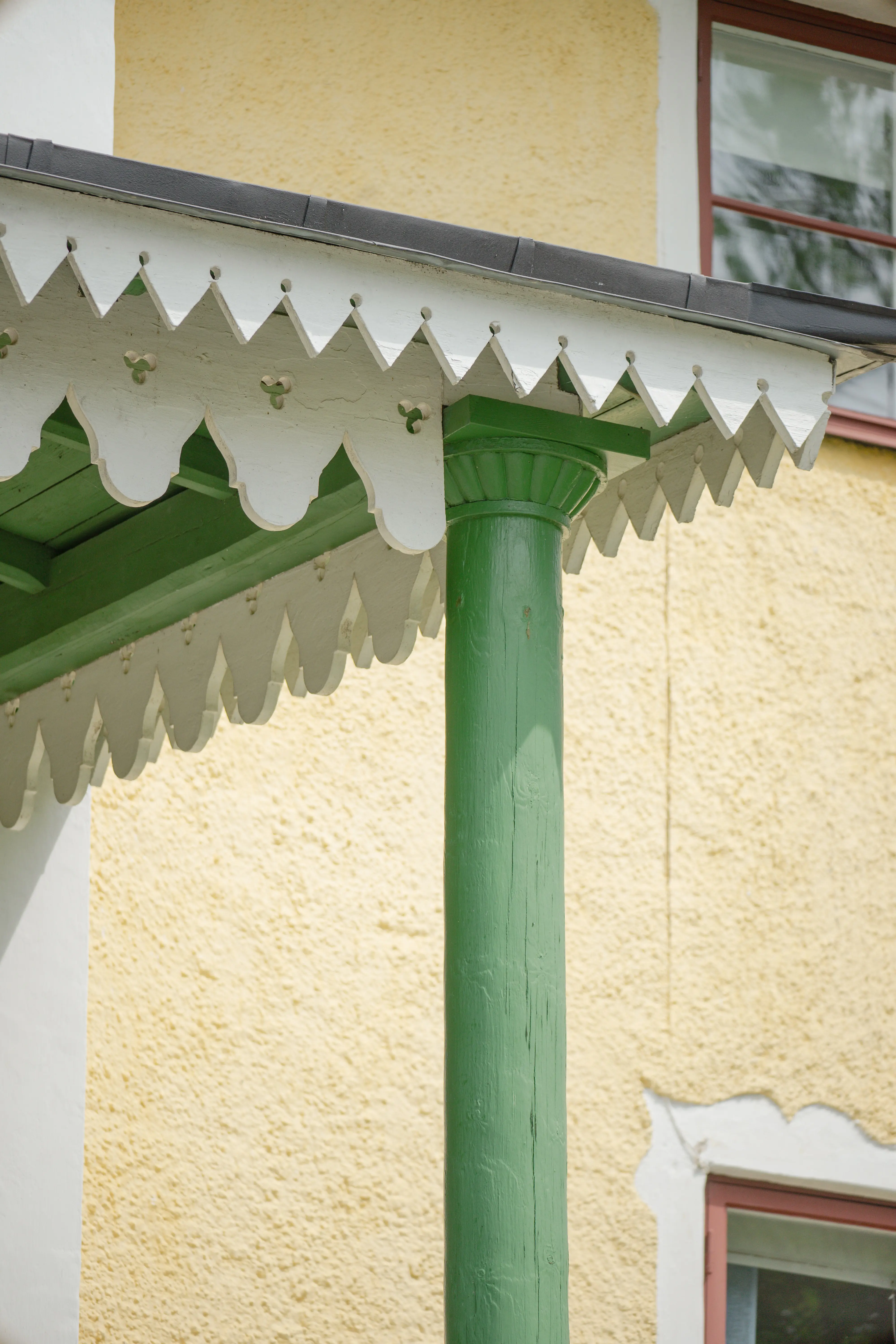 Landsberga. Detalj av stora huvudbyggnadens veranda som är grönmålad med vit snickar-glädje.