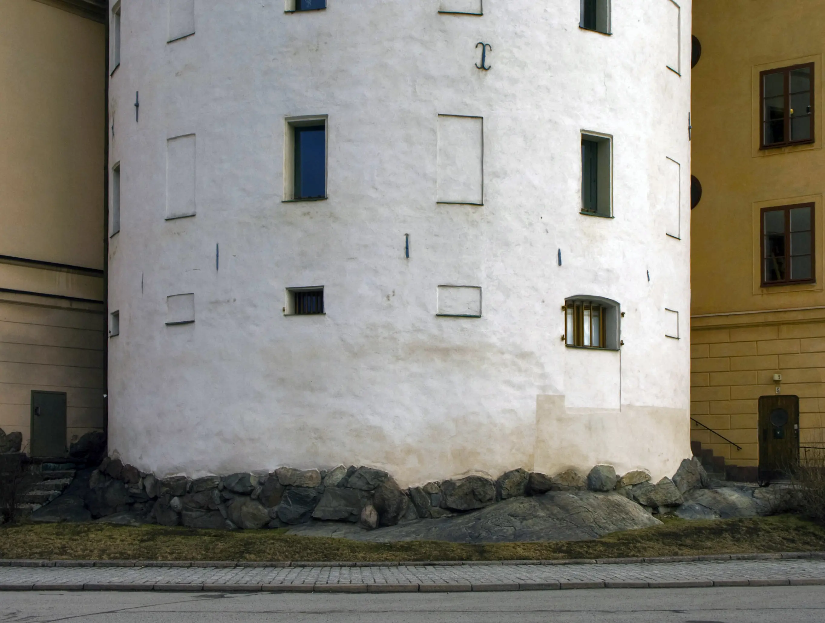 Birger Jarls torn, den nedre delen. Grunden består av urberg och stenblock. På den vita fasaden sitter enkla, svarta ankarslut.
