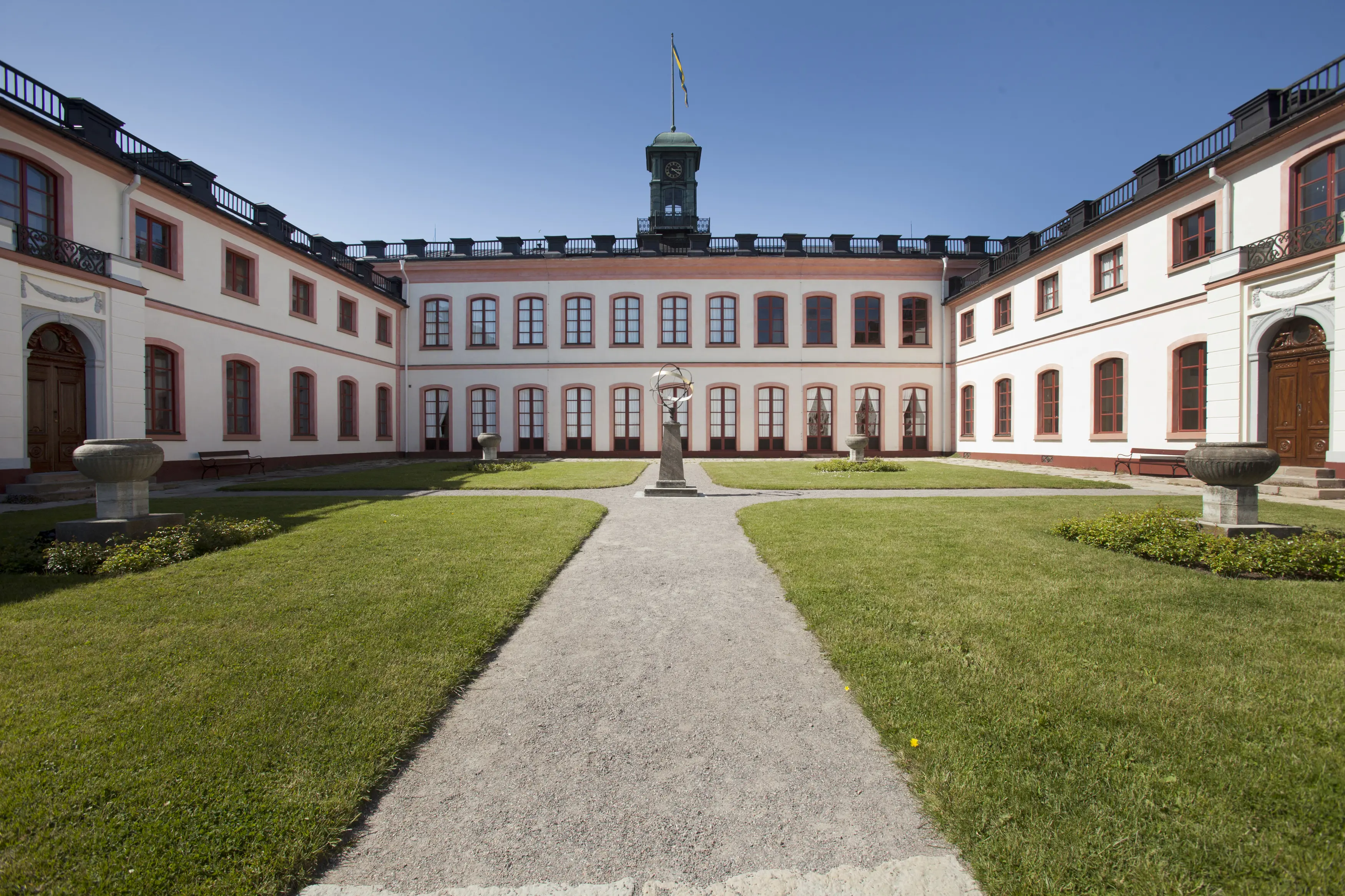 Tullgarns slott, borg-gården. Gårdens fyra gräsytor skiljs åt av grusgångar. Gär gångarna kosrsas står ett solur.