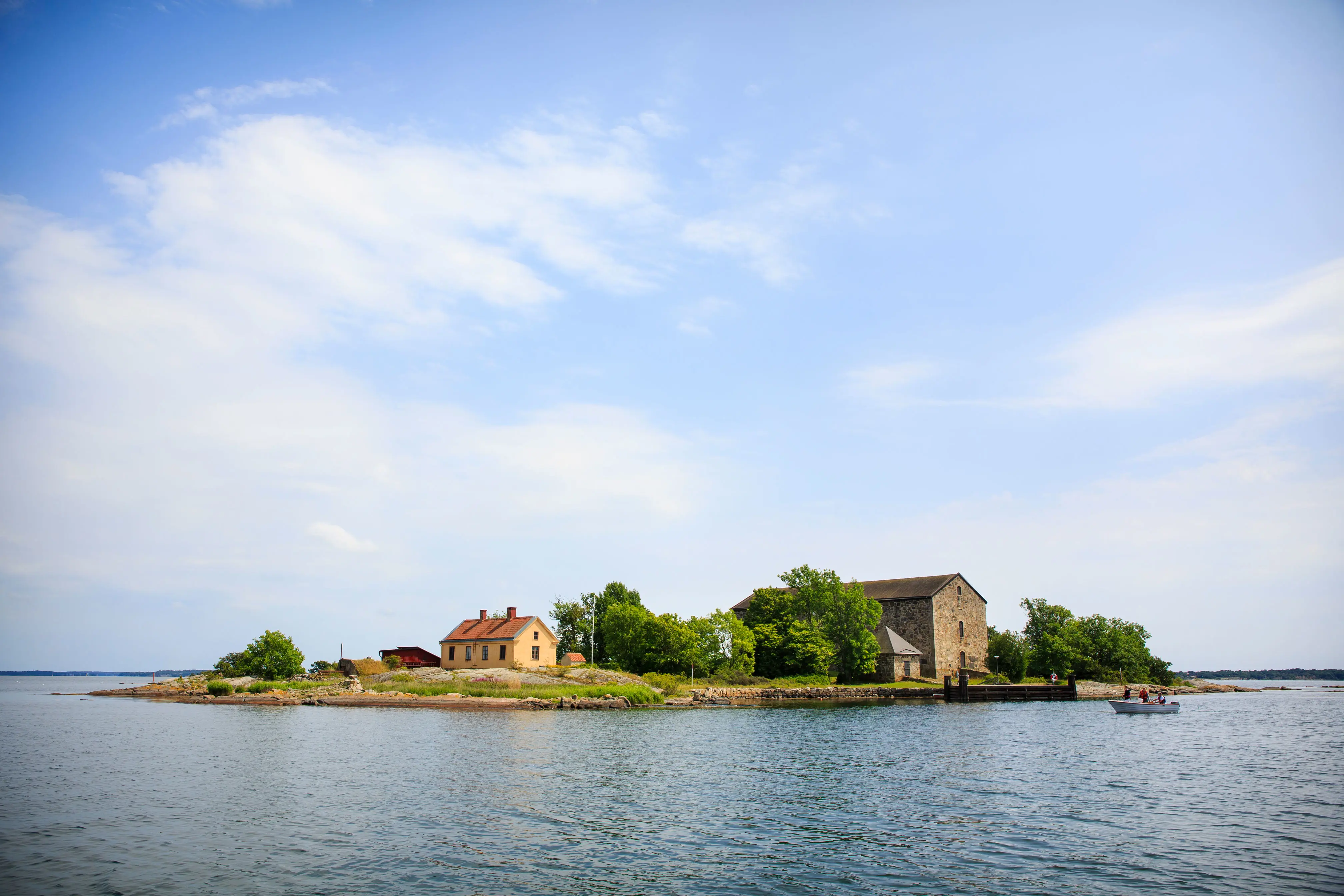 Ö med hus i hav med blå himmel