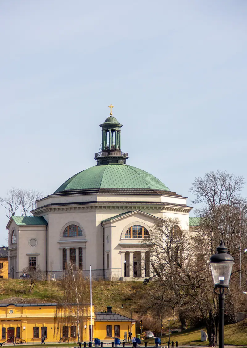 Skeppsholmskyrkan tronar på en höjd. Den åttakantiga kyrkan har en kopparklädd kupol och en hög lanternin på taket.