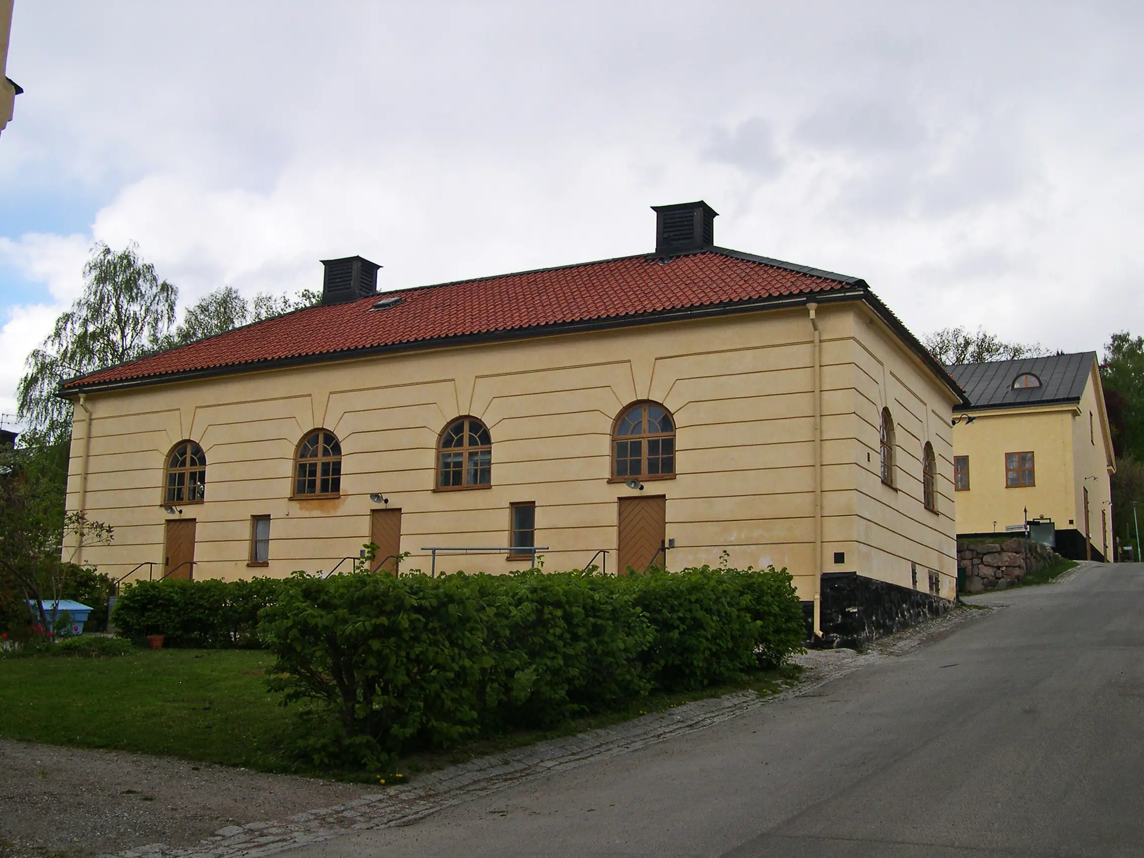 Drabantstallet på Malmen vid Drottningholm. Låg byggnad med gulputsad fasad, beläget i en backe.