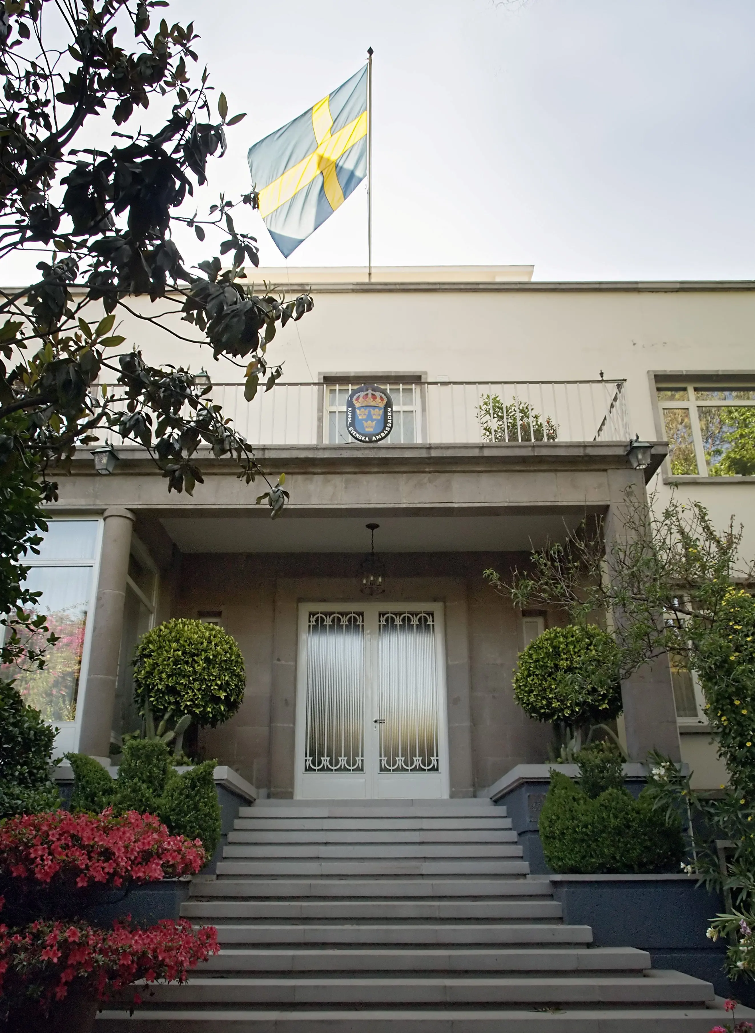 Ambassanläggning, Mexiko City. En trappa kantad av blomplanteringar leder upp till kansliets entré, som ramas in av en stenveranda.