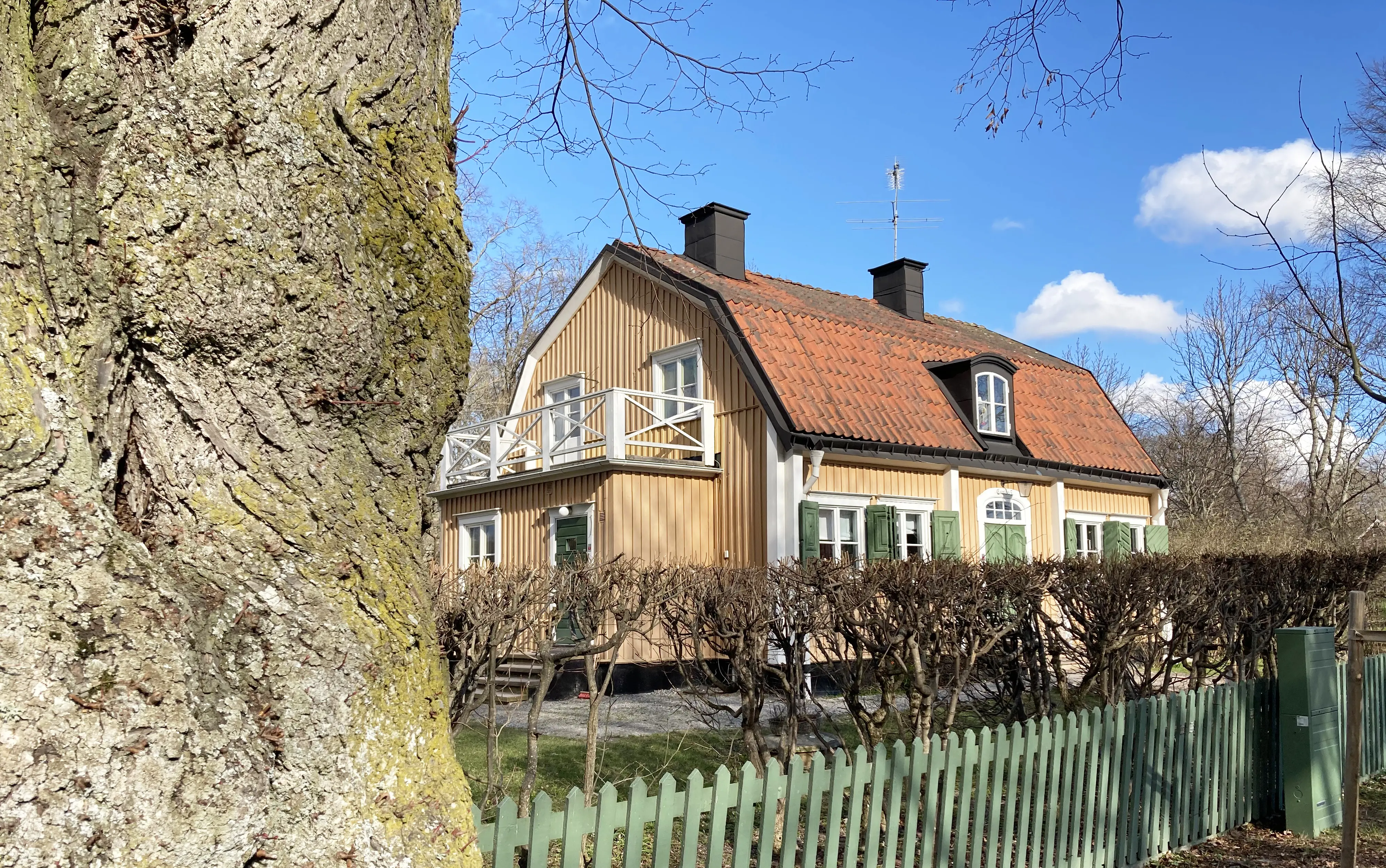 Kanton 5. Gult tvåvåningshus med gröna fönsterluckor. På det brutna tegeltaket sitter en tak-kupa. Gaveln har en liten utbyggnad med balkong.