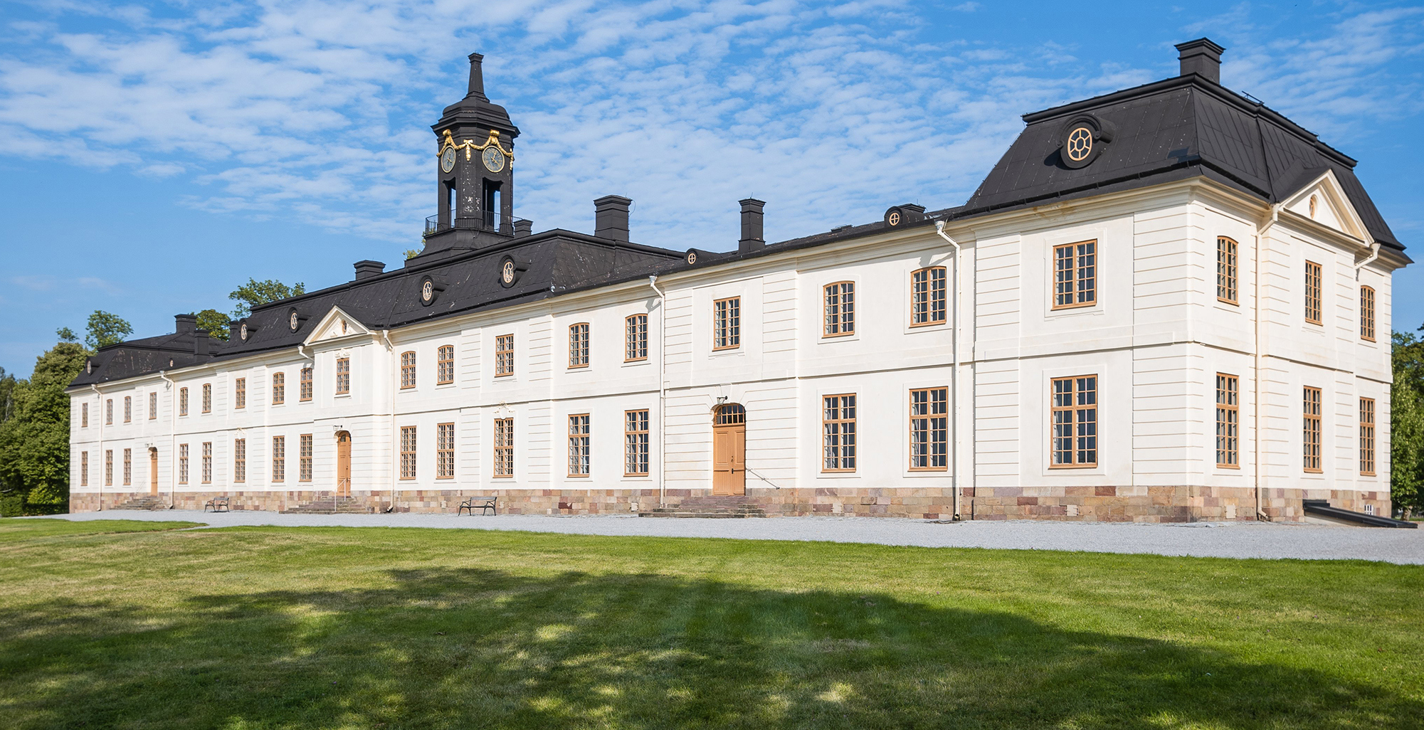 Svartsjö slott sett snett framifrån med en gräsyta i förgrunden. 
