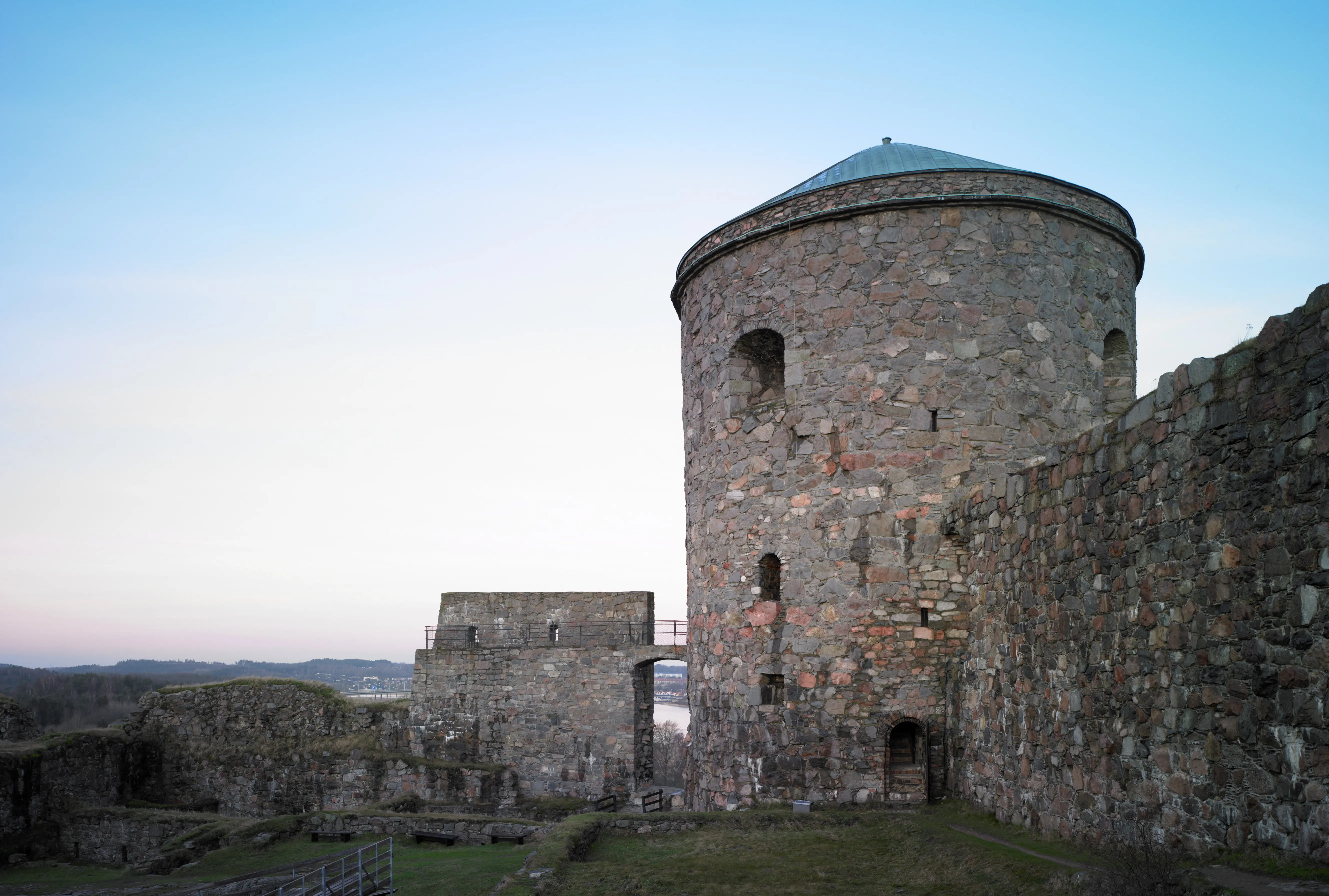 Bohus fästning, medeltida försvarsverk i sten. Ett runt torn är intakt, murarna är gräsbeväxta och delvis raserade.