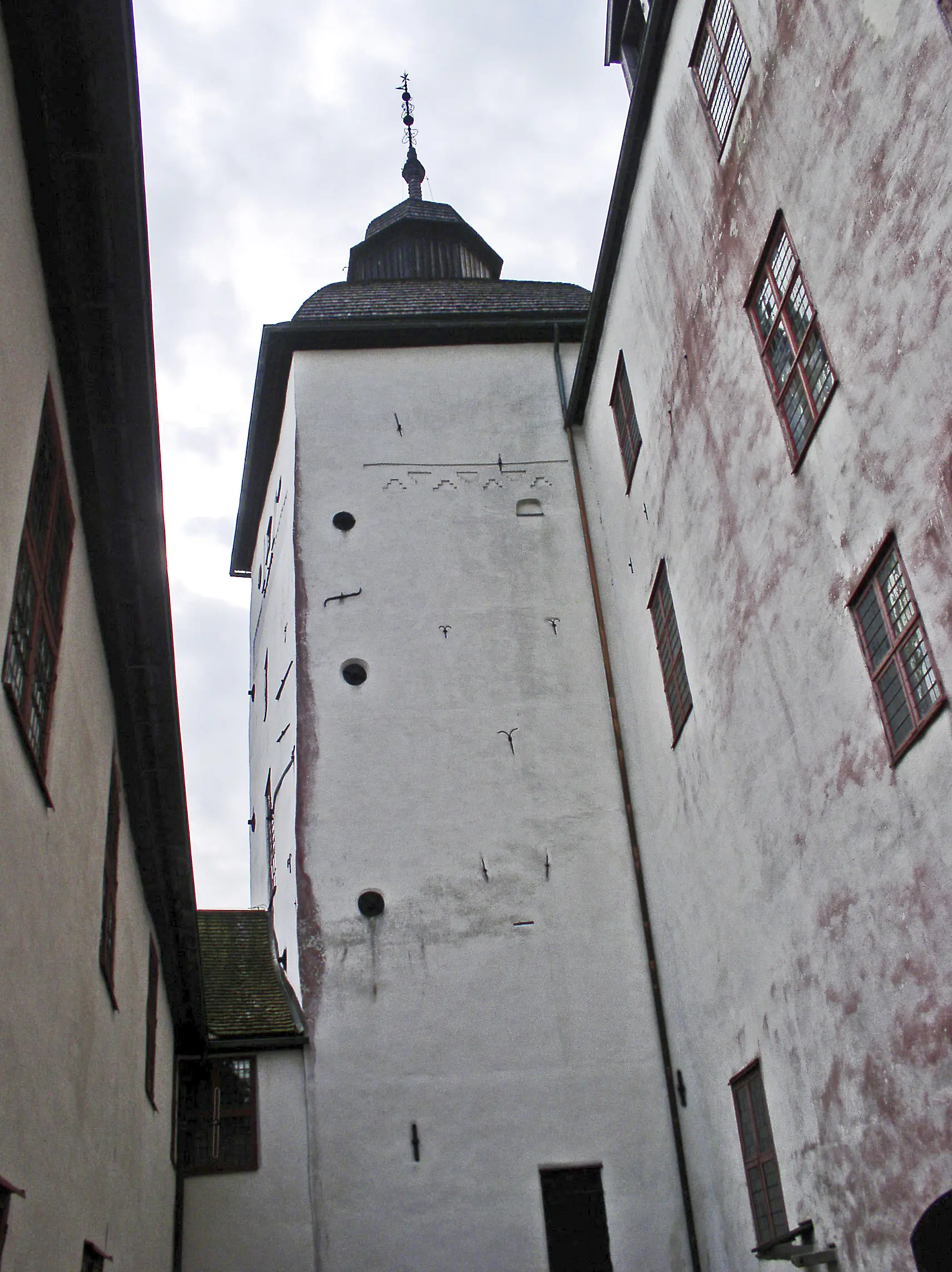 En hög vit kyrka med svart tak. Kyrkans fasad är rödfläckad på grund av röda alger.