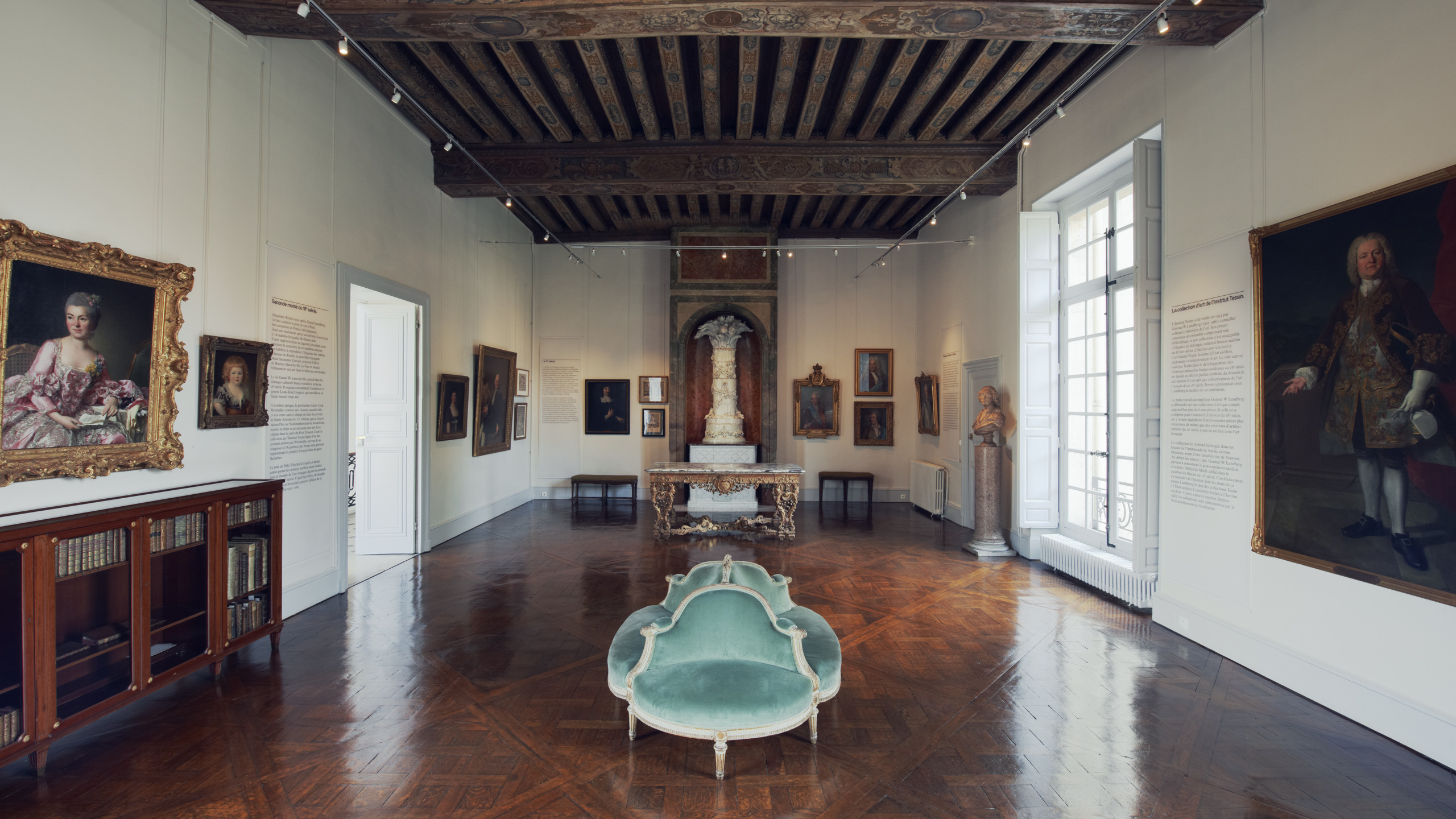 Svenska institutet i Paris. Utställningsrum med mönstrat trägolv och rejäla, målade takbjälkar. På väggarna hänger porträtt.