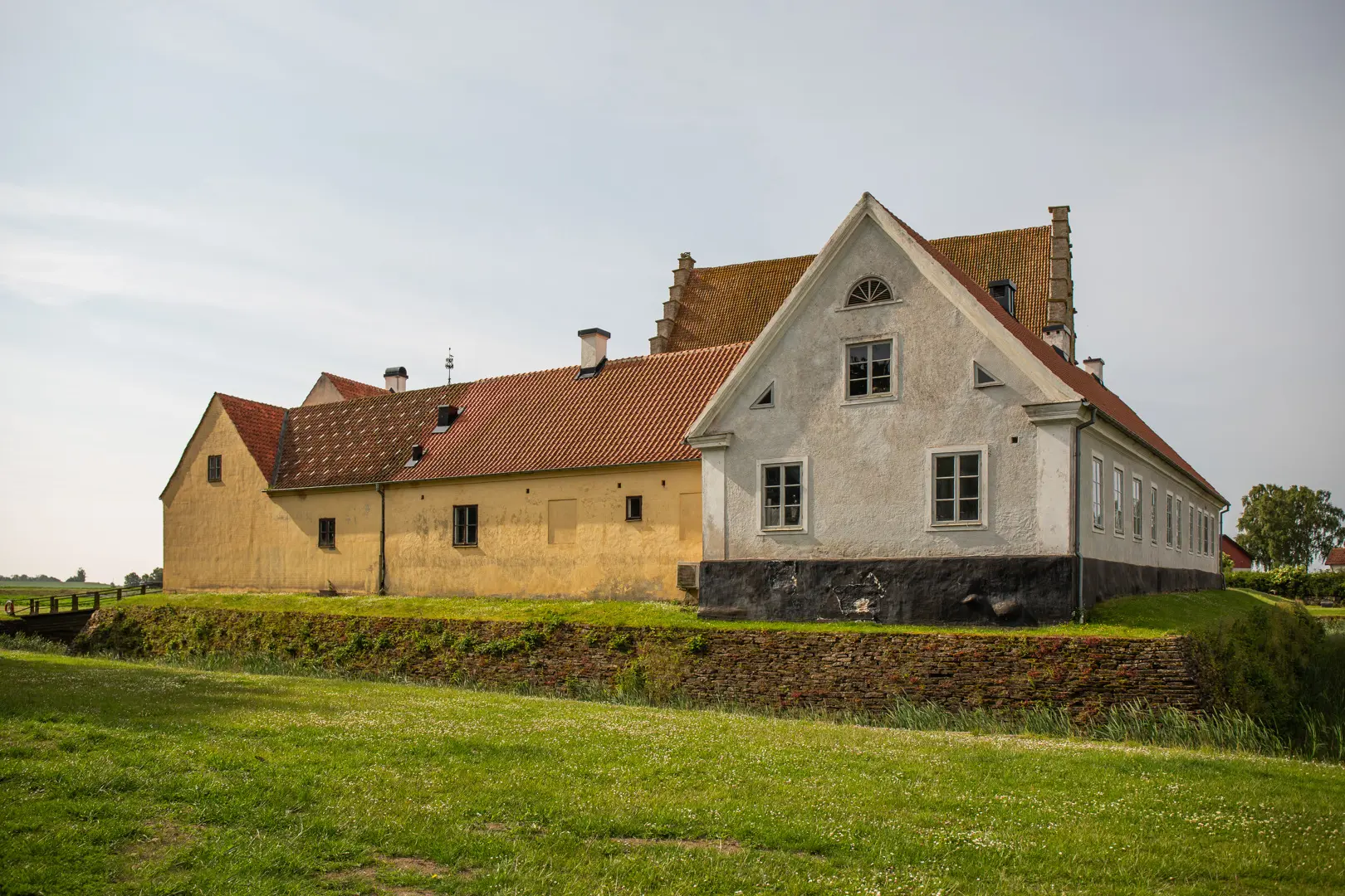 Ett gult och ett vitt äldre hus där borgens tak skymtar i bakgrunden.