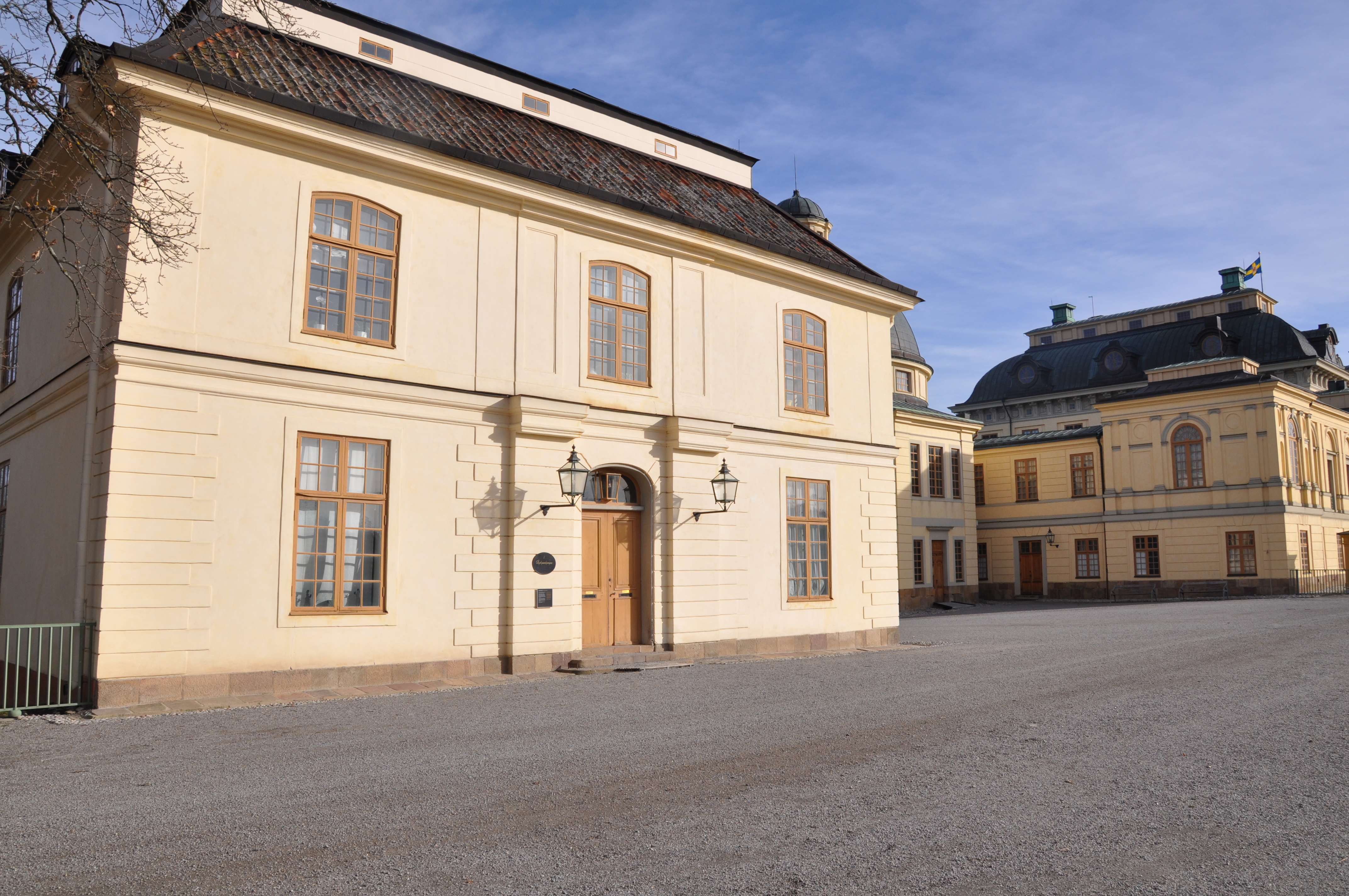 Hus med säteritak. Fasaden är i ljus puts. Dörr och och fönsterstommar är målade i en orange eller brun kulör.