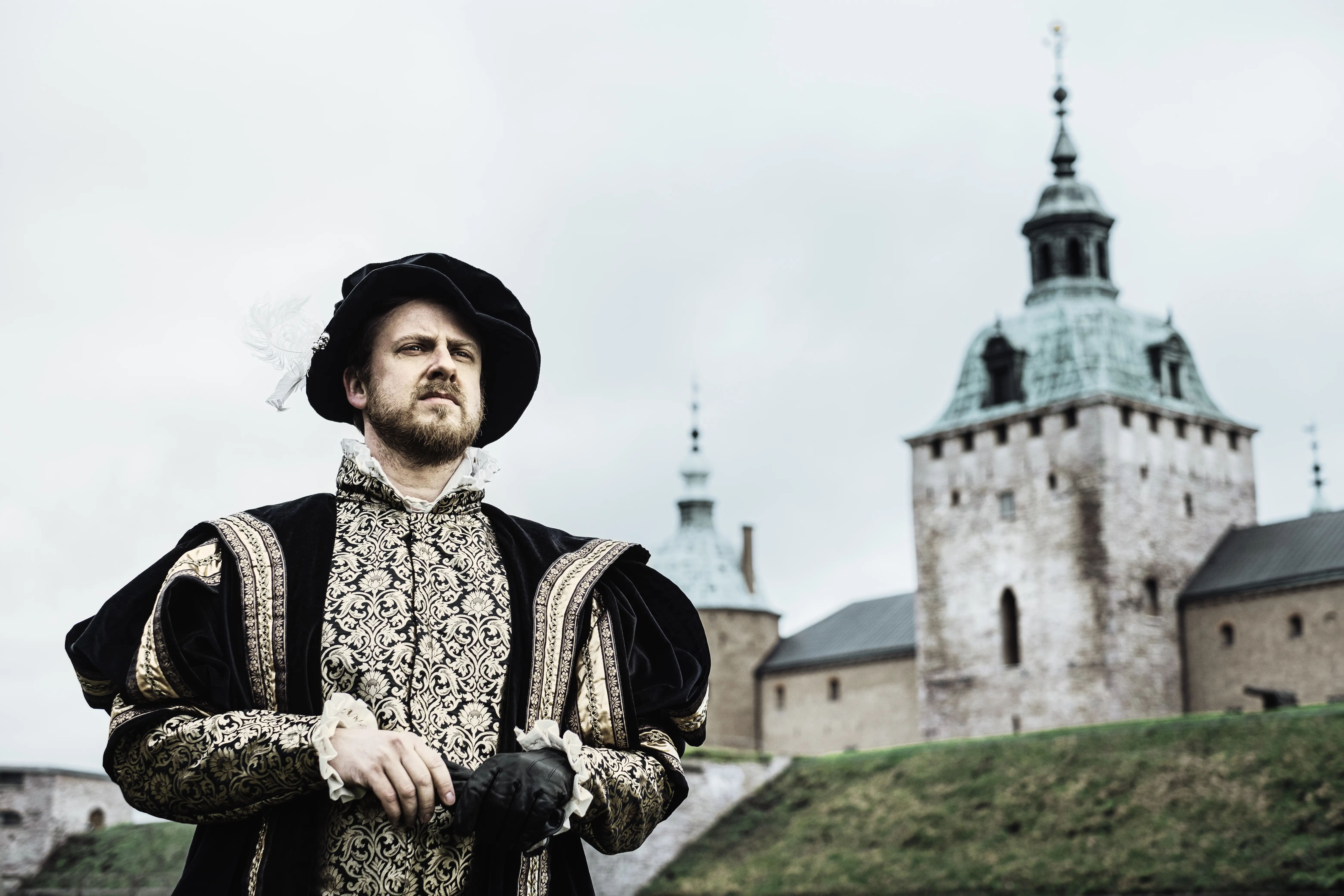 En person utklädd till Gustav Vasa står vid vallgraven med Kalmar slott i bakgrunden.