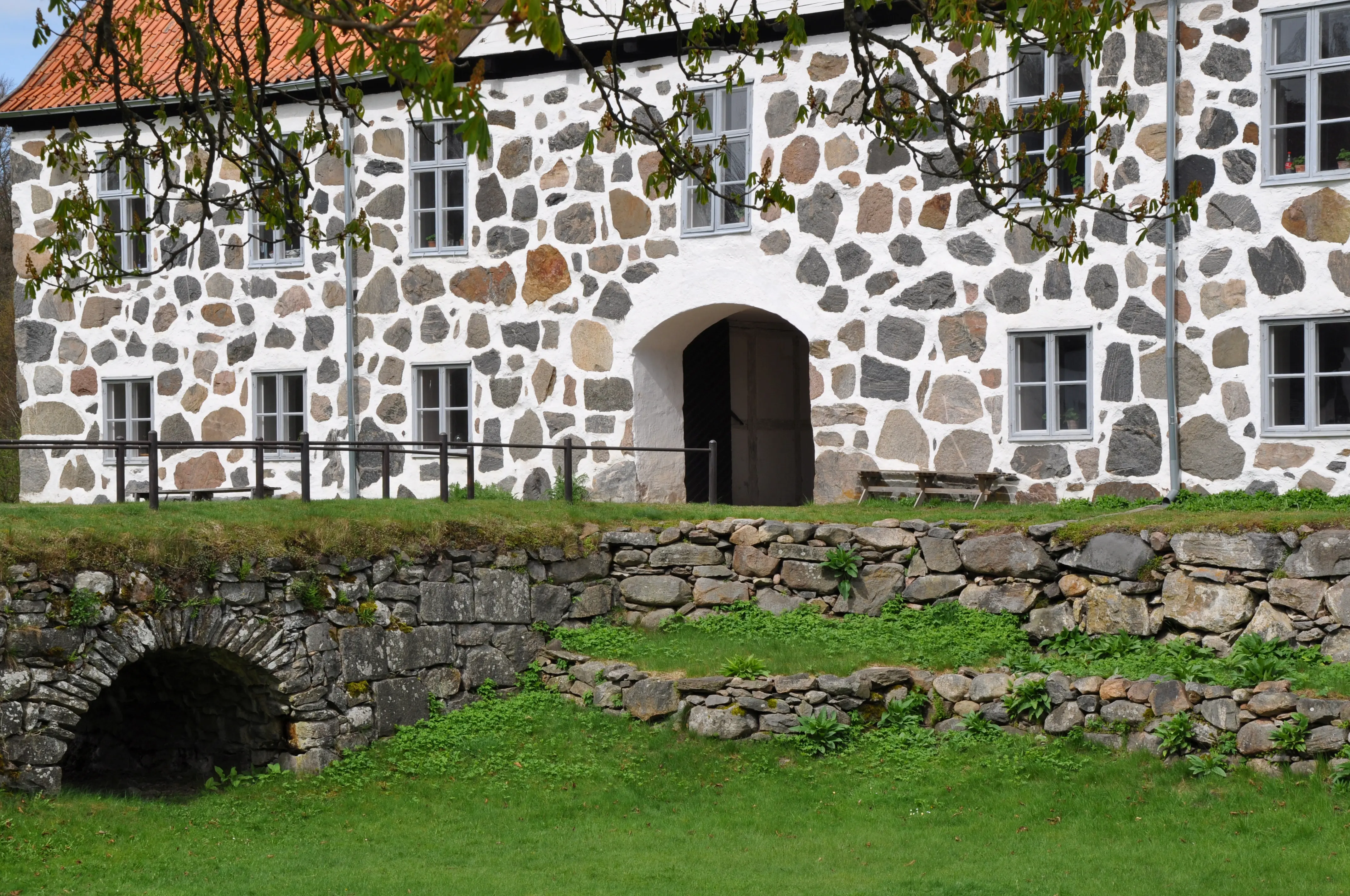 Hovdala slott, arrendatorflygeln. Stenbyggnad i två våningar. I förgrunden den torrlagda vallgraven och en valvbro i sten.