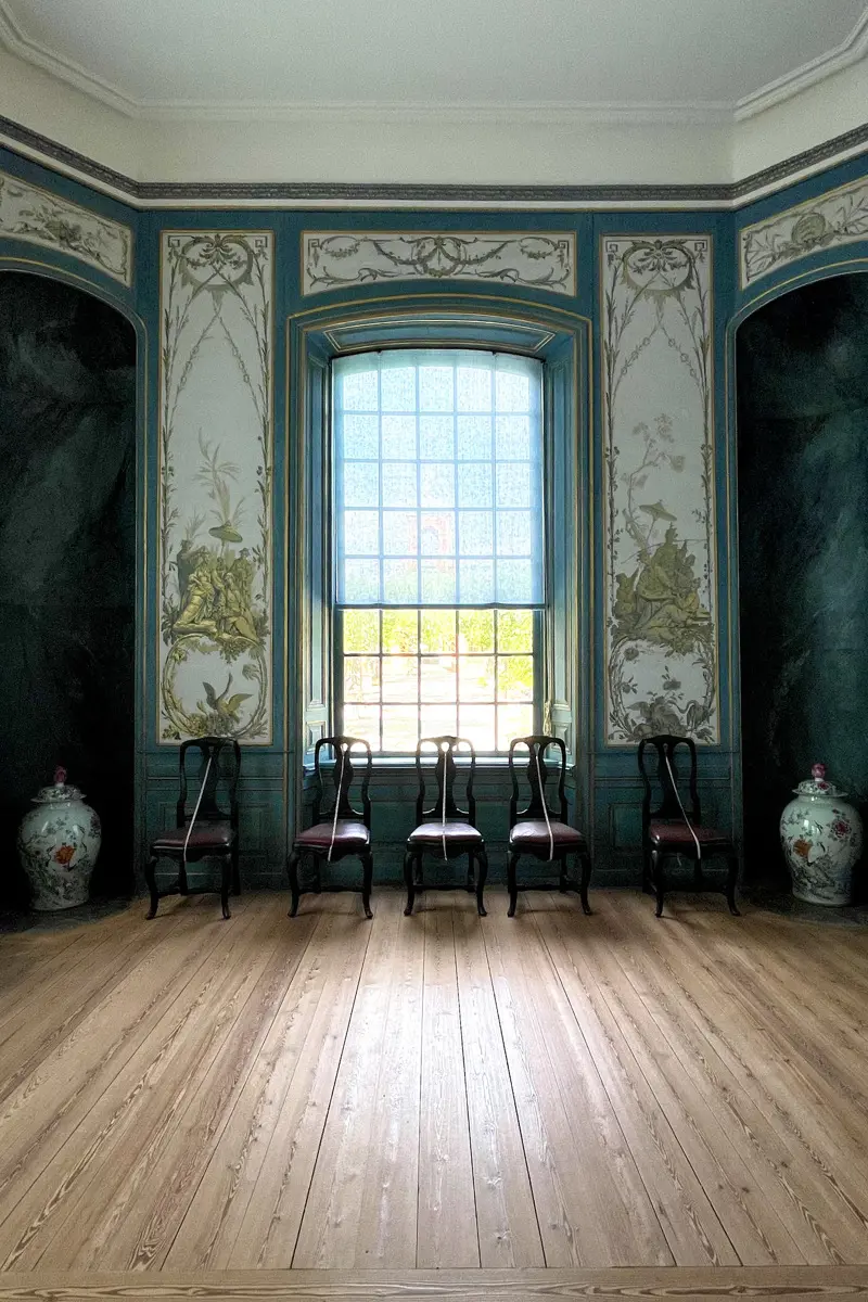 Interiör från Kina slott. En sal med trägolv, tapeter med växtmotiv och ett stort spröjsat fönster.