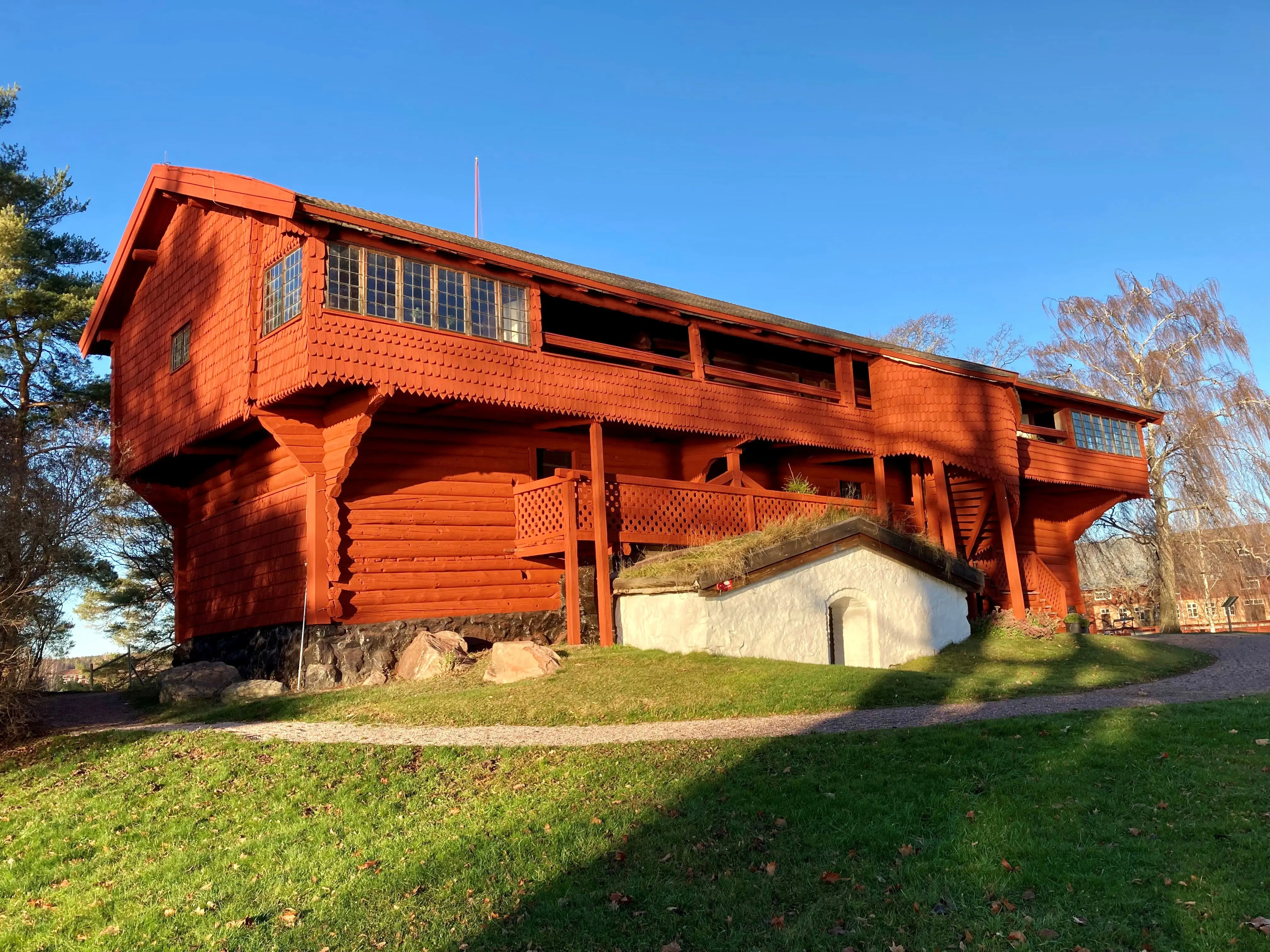 Rött timmerhus på grön gräsmatta.