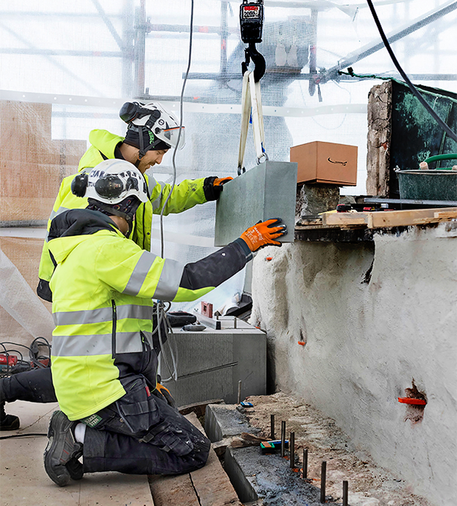 Hantverkare lyfte nyhuggen sten på plats på Stockholms slott.