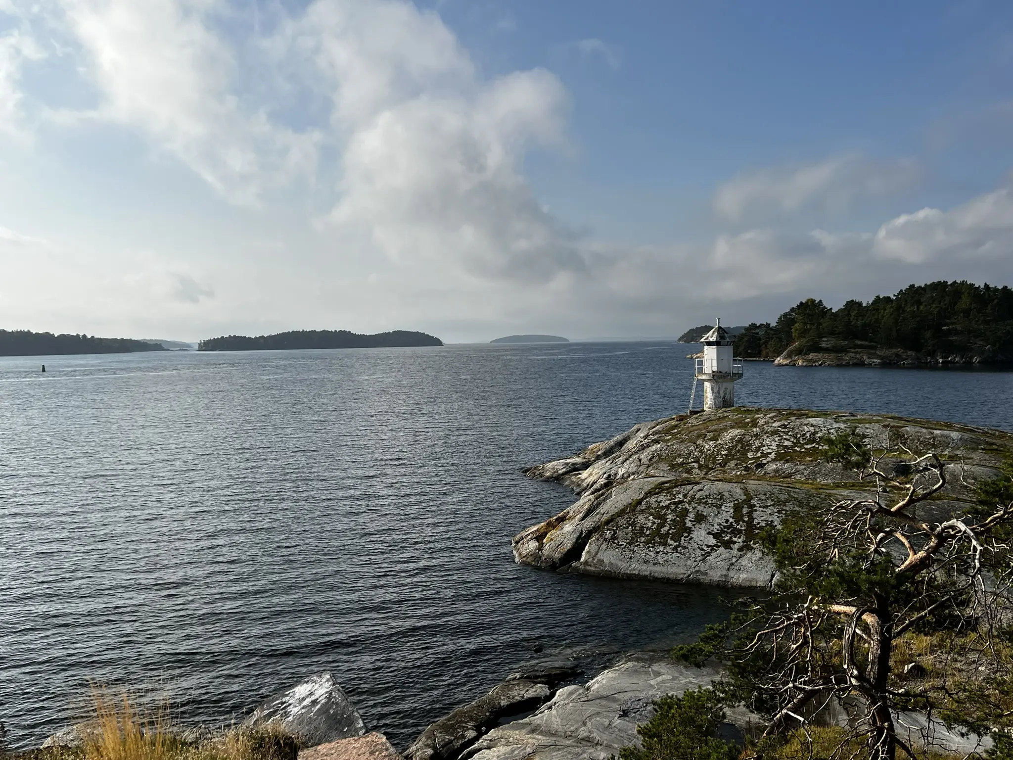 Dalarö skans. Utsikt över fjärden från öns södra udde. Ett litet vitt fyrtorn står längst ute på klippan. Höst.