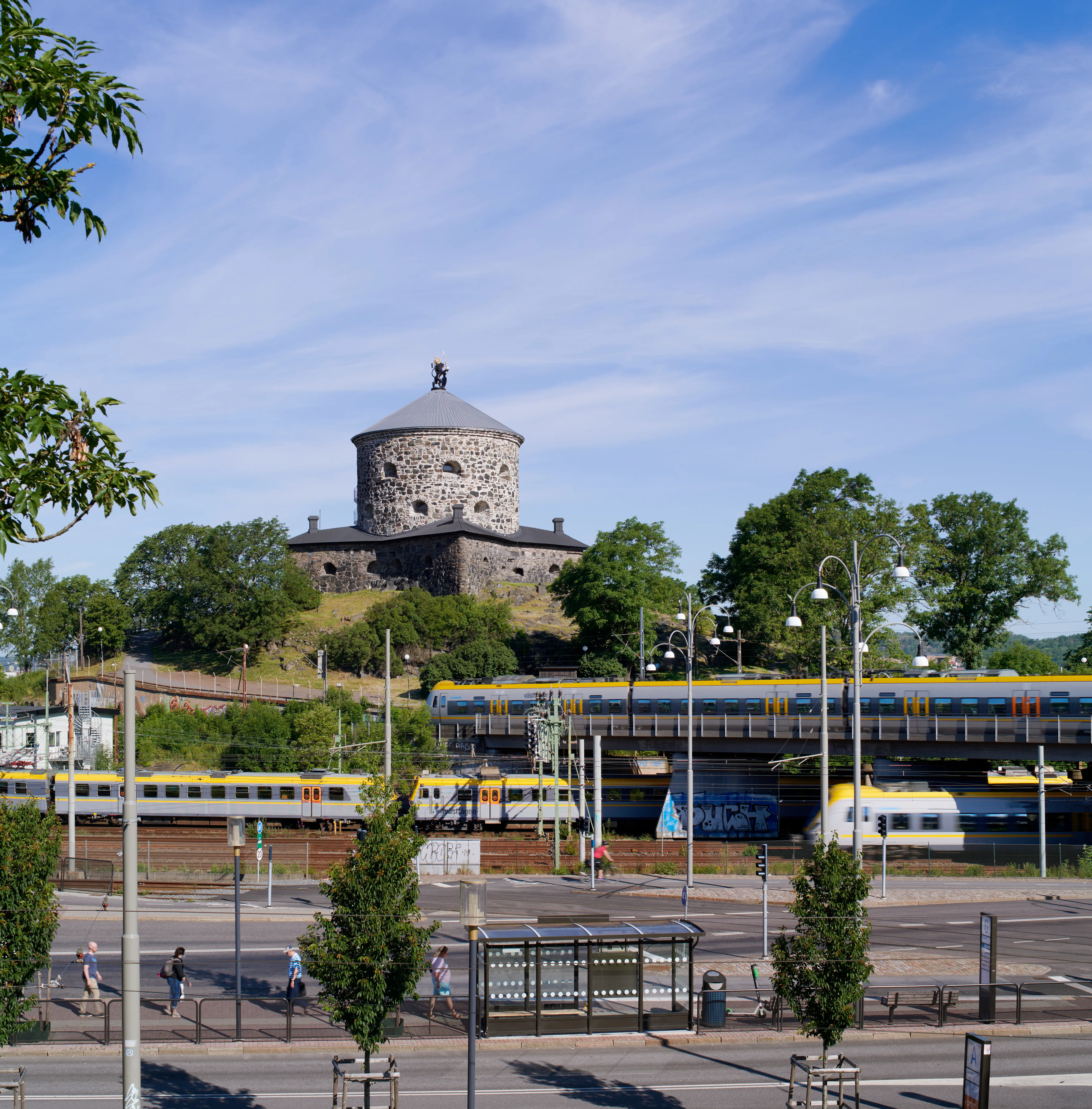 Skansen Lejonet på en höjd ovanför tågtrafik och bilvägar. Sommar och grönska.