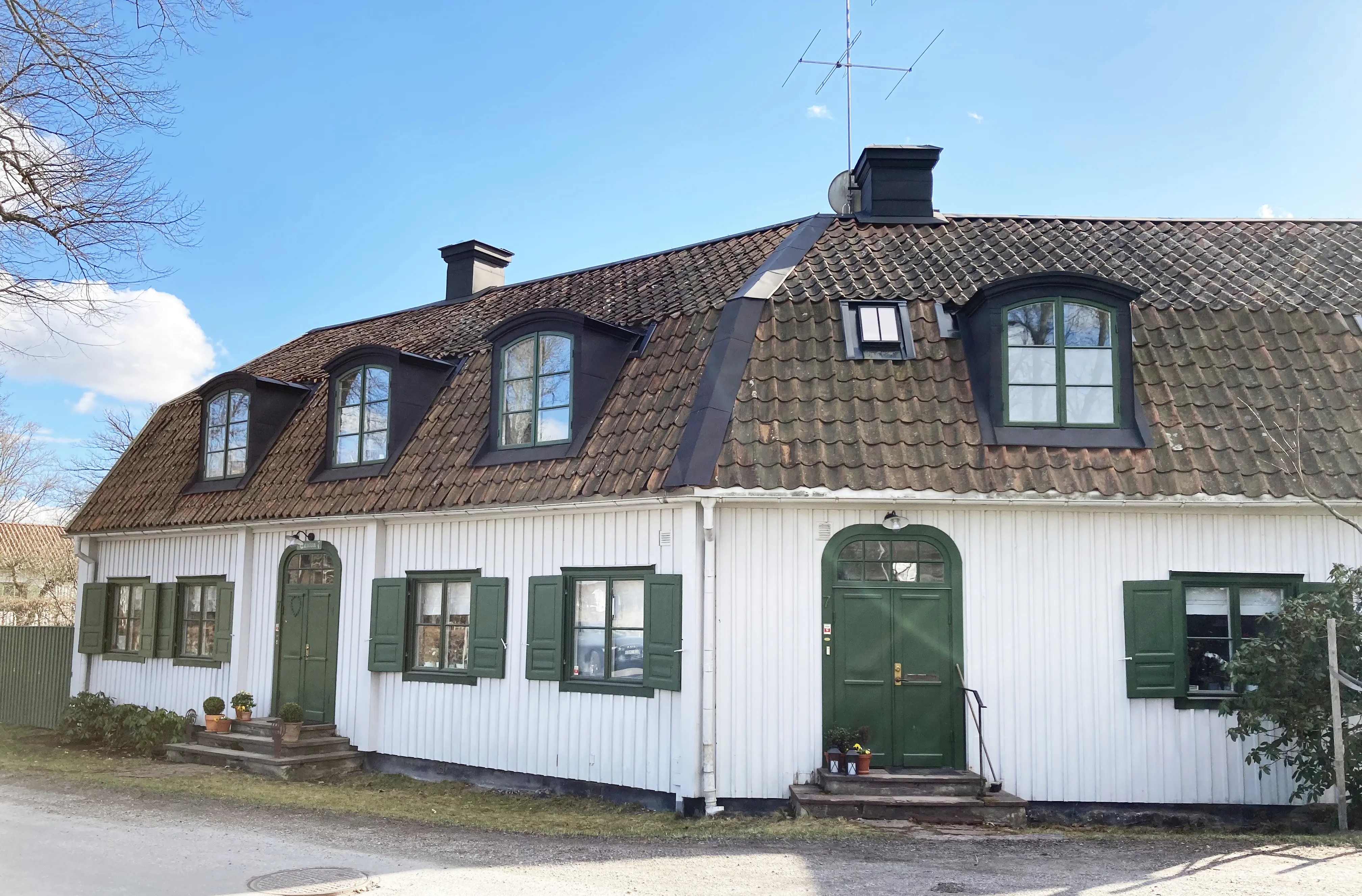Kanton 7 och 8. Vita hus, sammanbyggda i vinkel, med gröna fönsterluckor. Tegeltaken har tak-kupor.