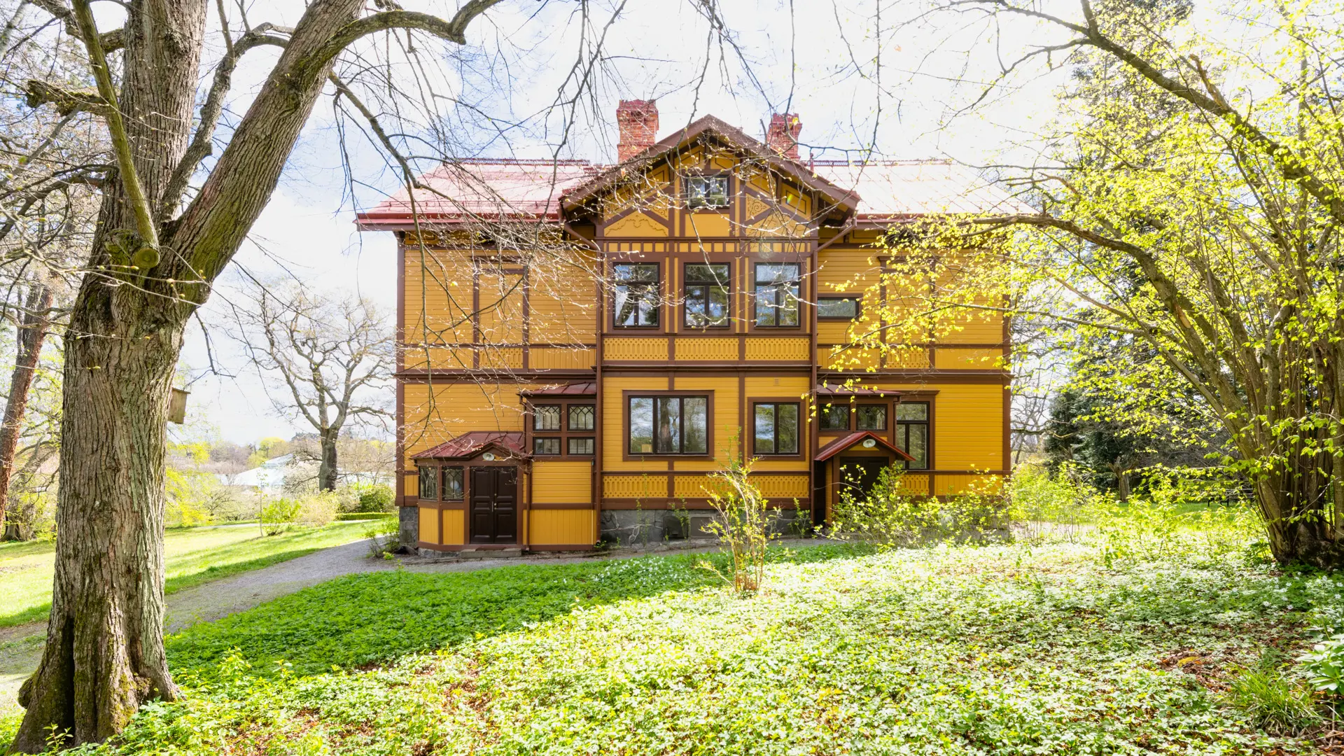 Bergianska trädgården, Professorsvillan. En gul trävilla med bruna snickerier. Vår och skir grönska.